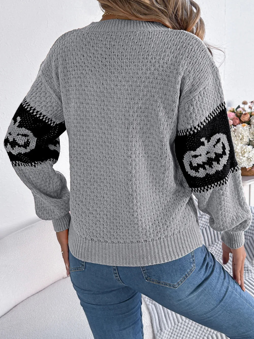 Gray long-sleeve sweater with black pumpkin designs on the sleeves.