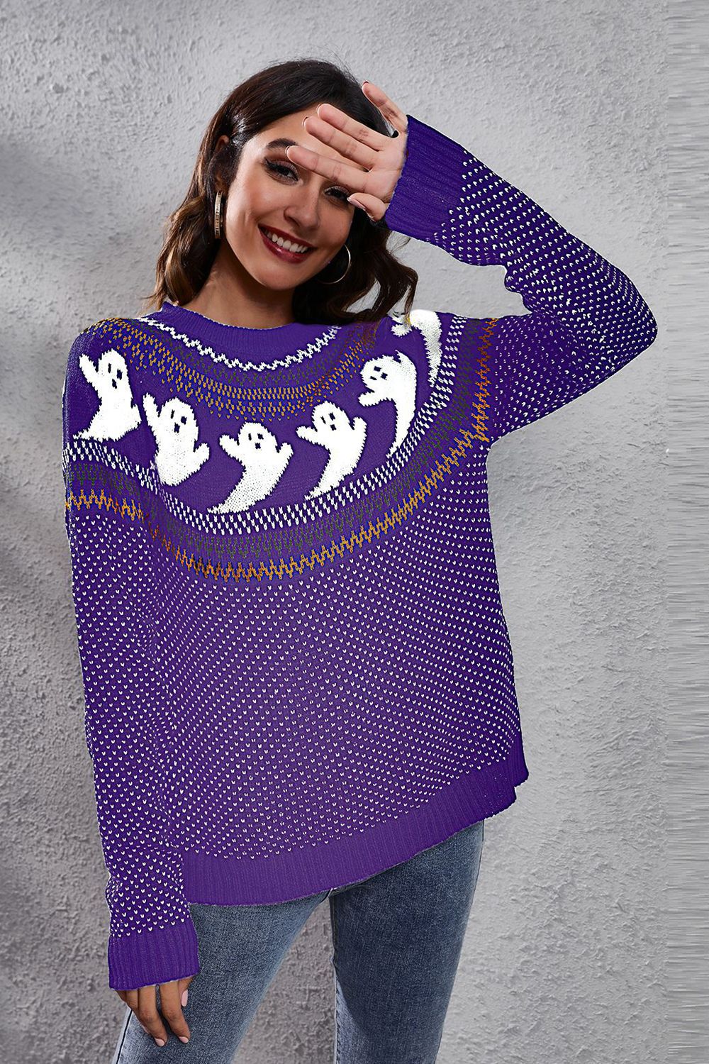 A woman smiles in a purple ghost pattern round neck long sleeve sweater.