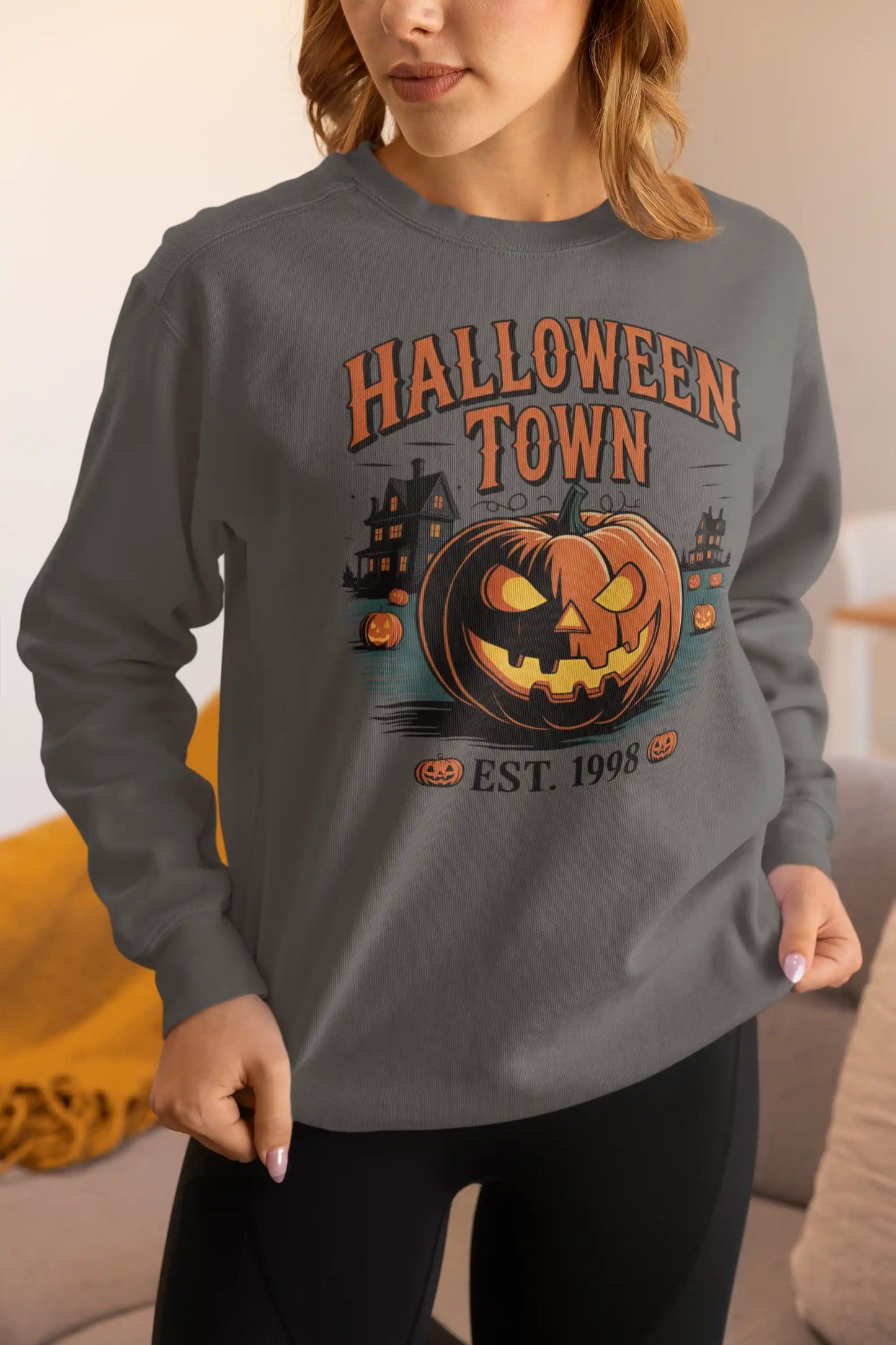 A woman wears a dark gray Halloween Town sweatshirt with a vintage pumpkin graphic.