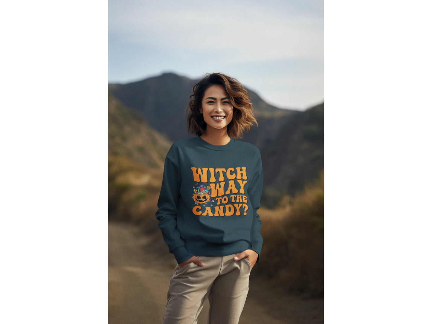 A woman smiles wearing a dark teal "Witch Way to the Candy?" Halloween sweatshirt.