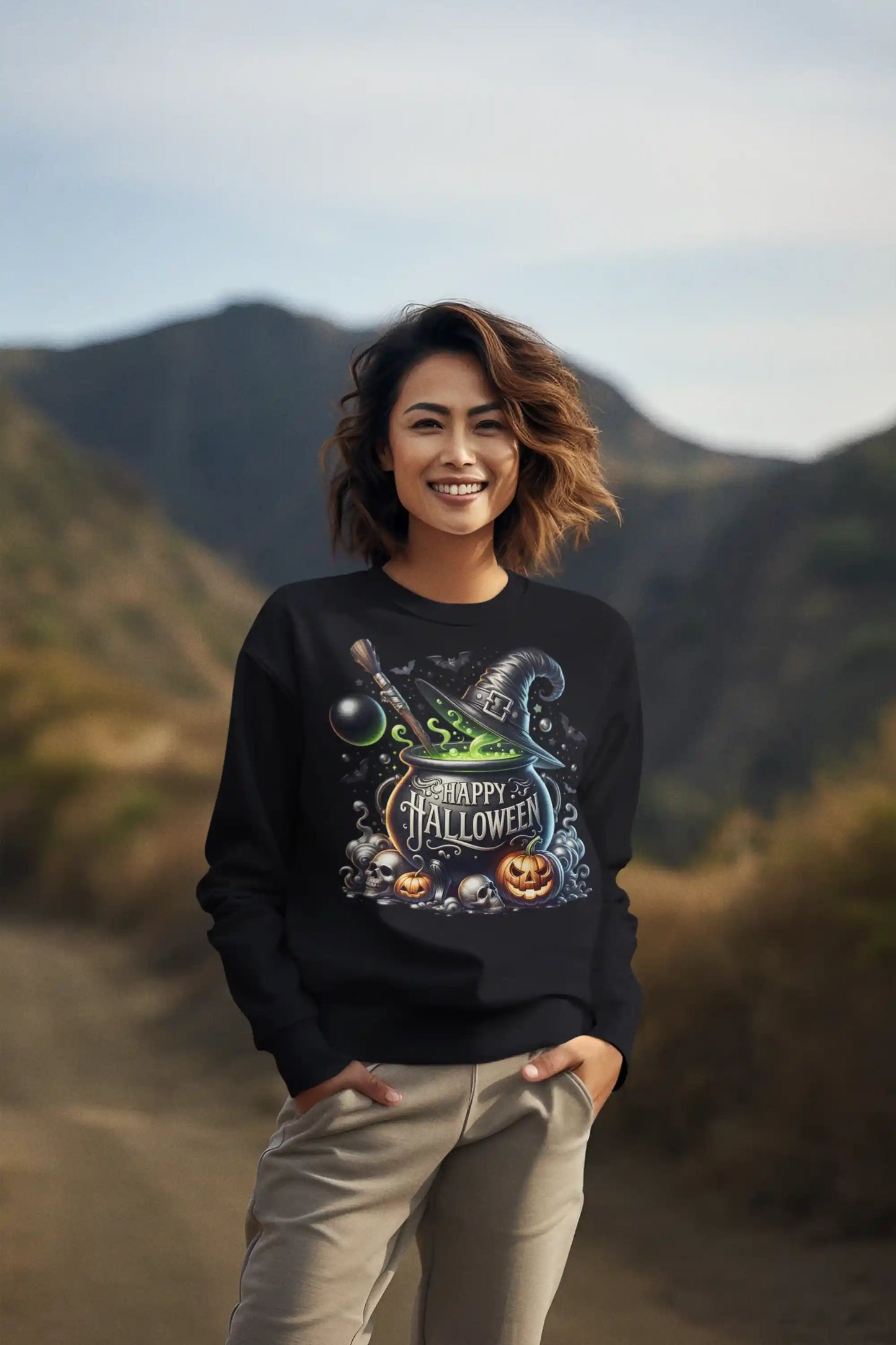 A woman smiles wearing a black sweatshirt with a Halloween cauldron design.