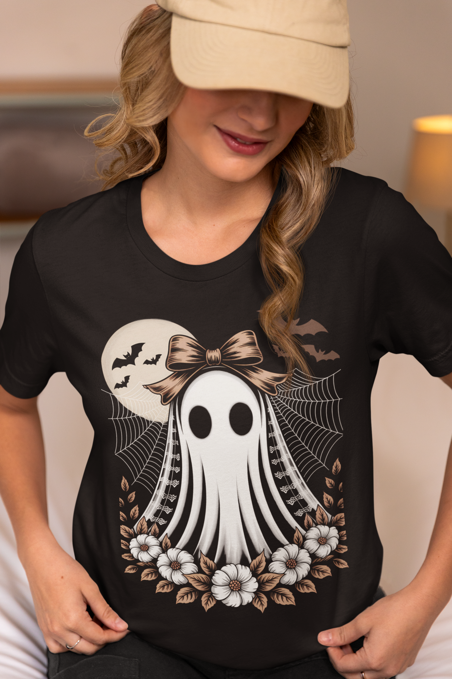 A woman in a beige cap and black t-shirt with a vintage ghost design.