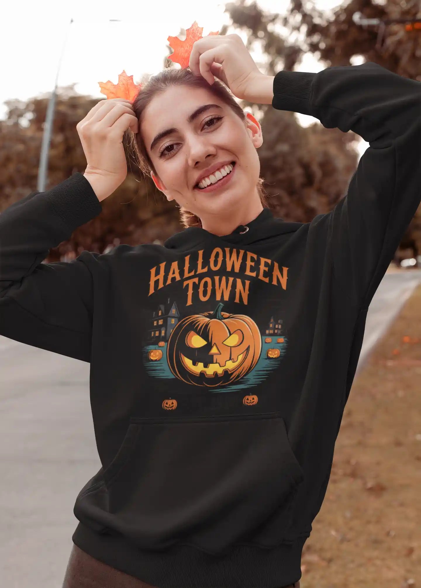 A woman smiles while wearing a black Halloween Town hoodie with a pumpkin graphic.