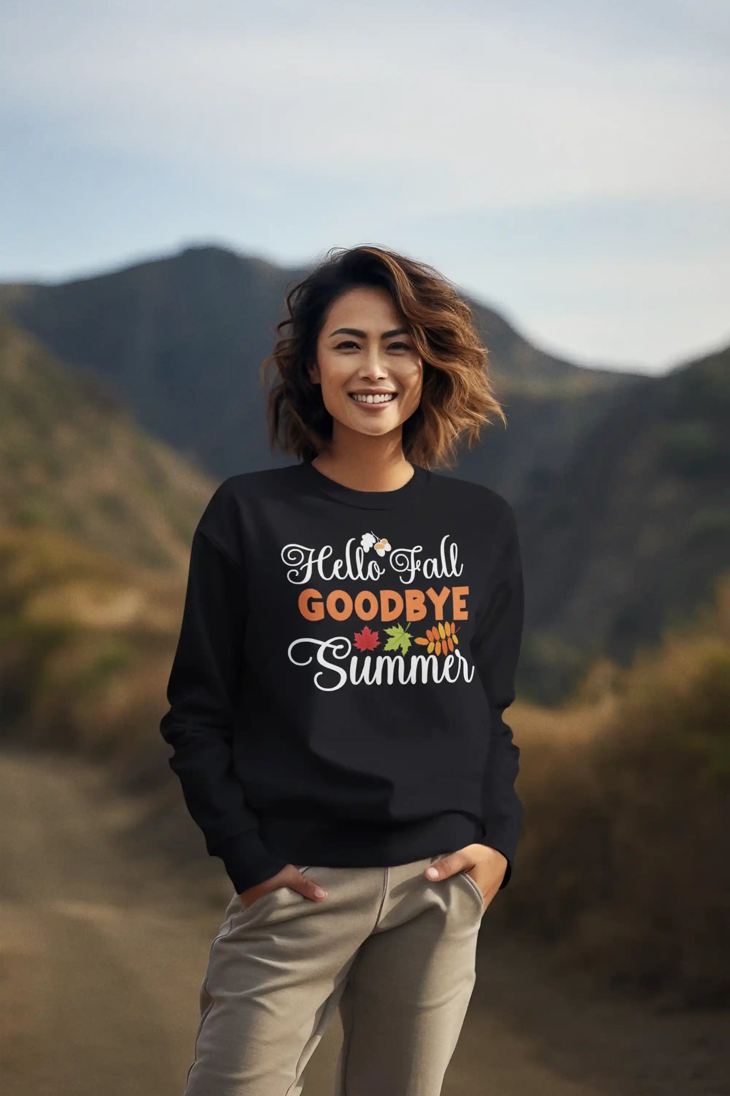A woman smiles while wearing a black "Hello Fall Goodbye Summer" sweatshirt.