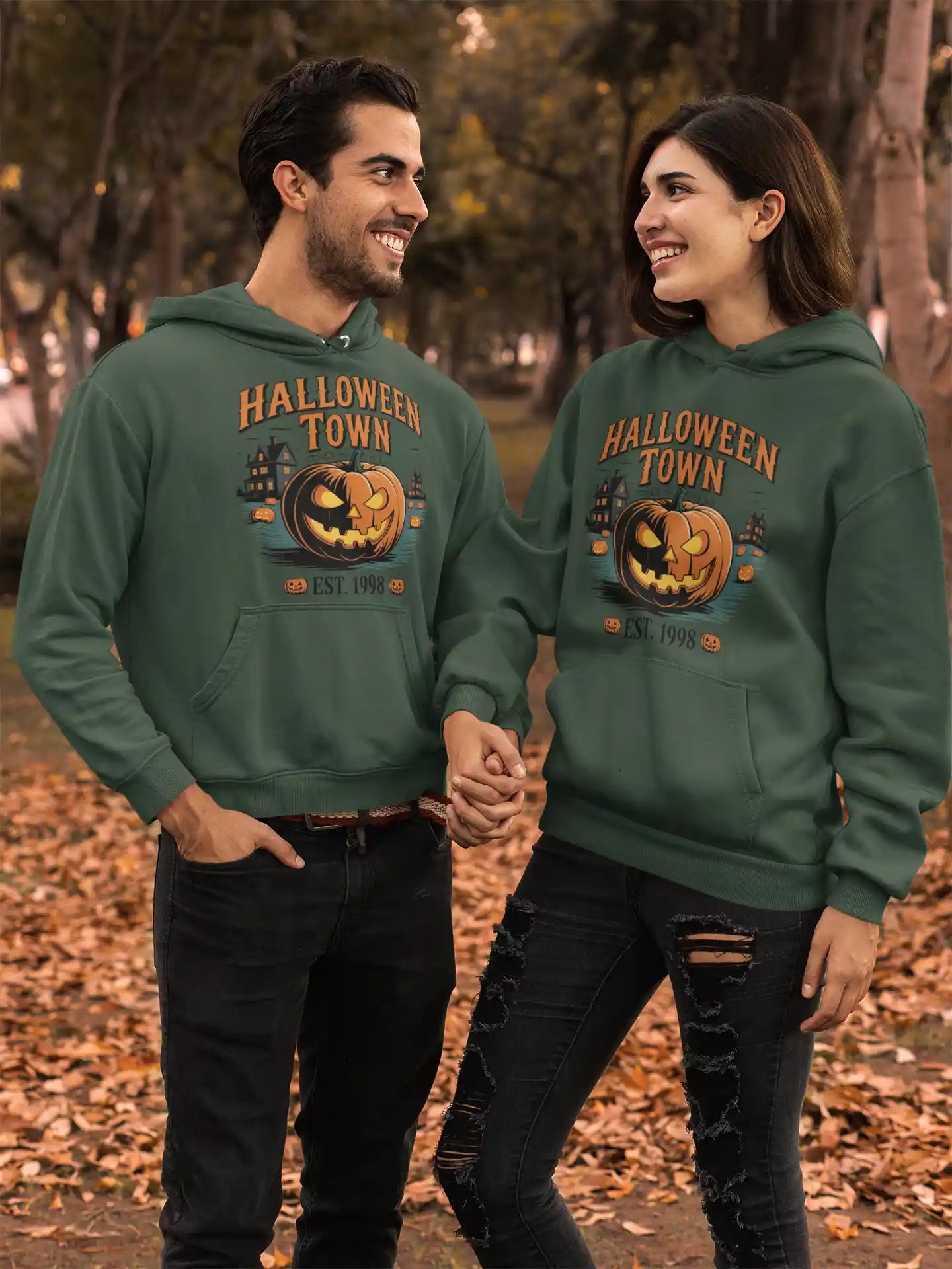 Two people wear matching green "Halloween Town" hoodies with a pumpkin graphic.