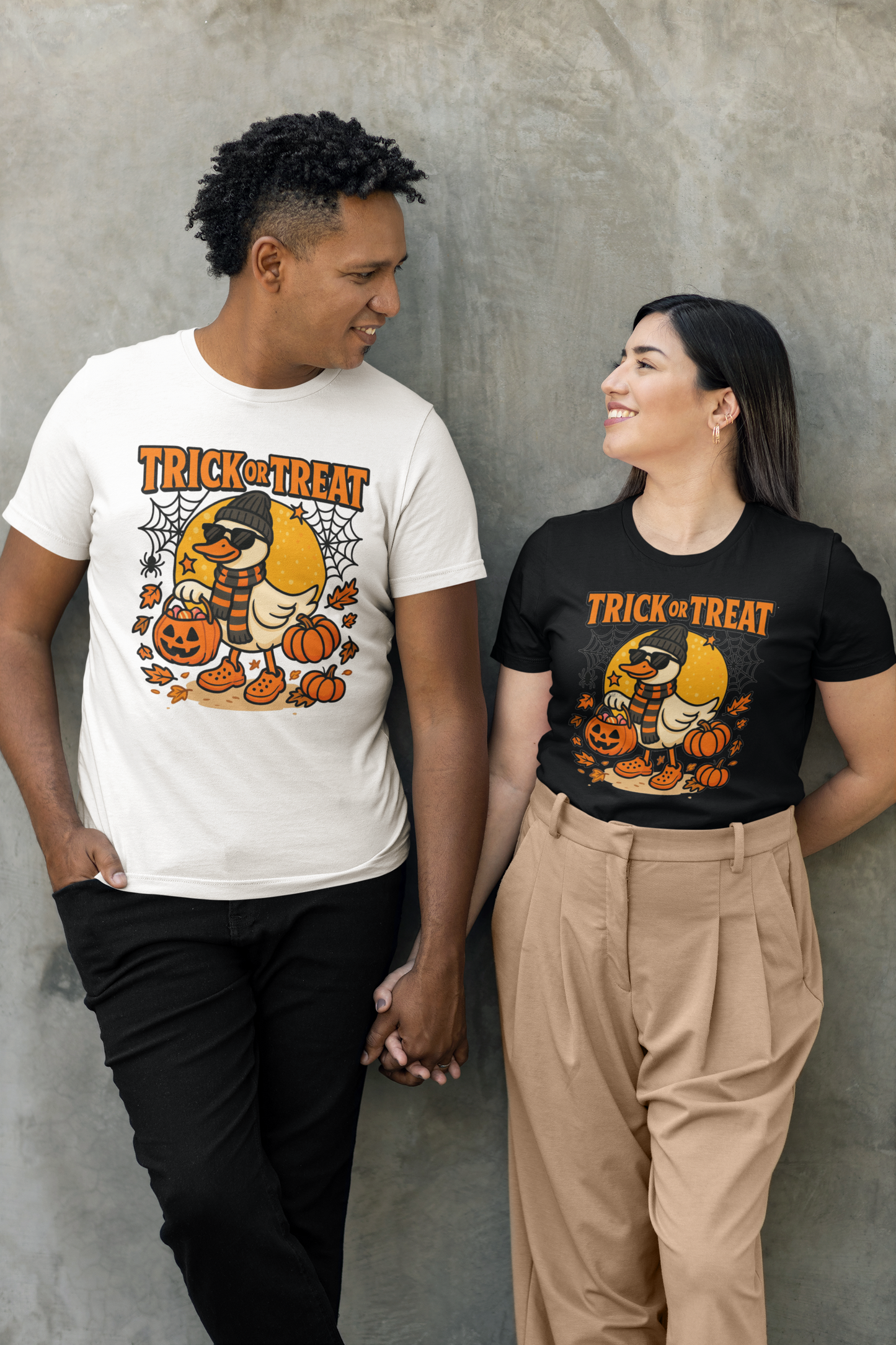 A couple wearing matching Halloween duck graphic t-shirts, holding hands.
