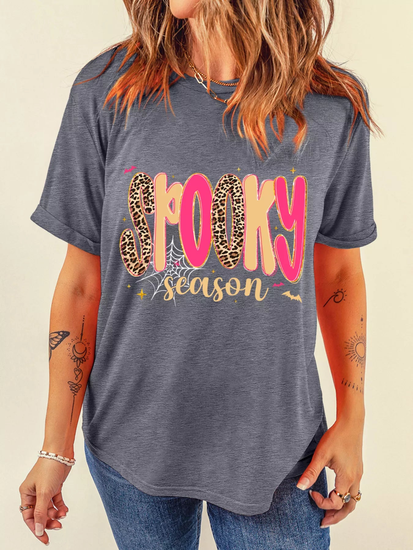 A woman wears a gray "Spooky Season" graphic t-shirt with leopard print letters.