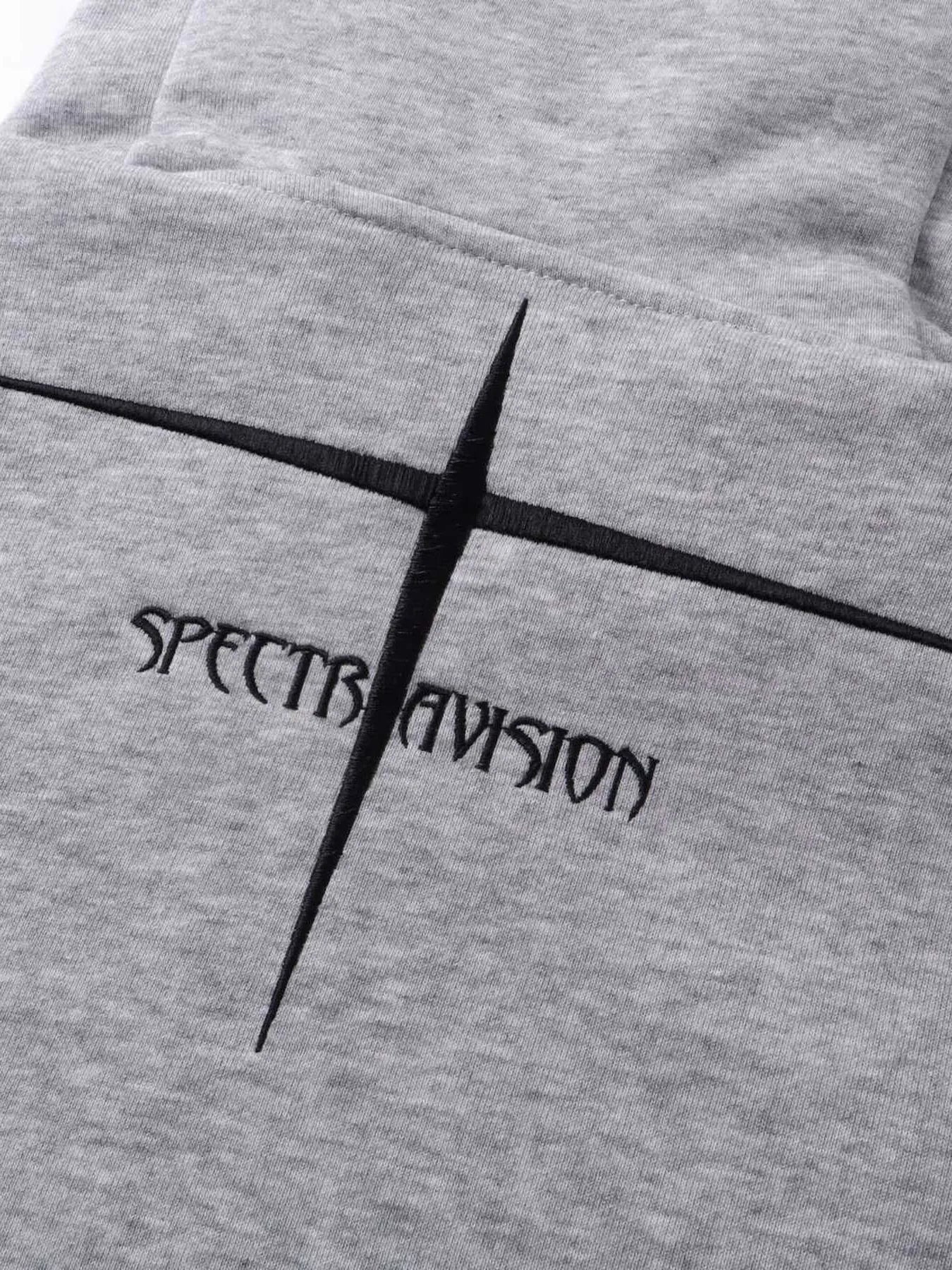 Close-up of a gray hoodie with black embroidered "SPECTRAVISION" text and cross design.
