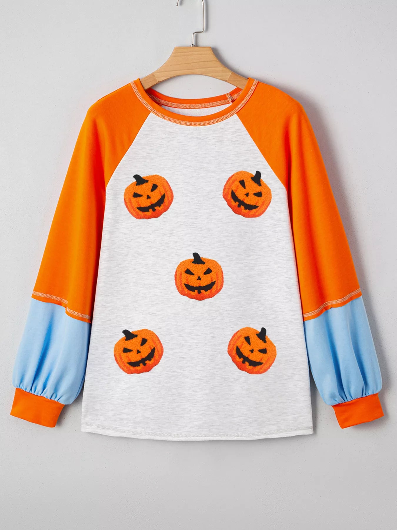 Halloween pumpkin print long sleeve t-shirt with orange raglan sleeves and blue cuffs.