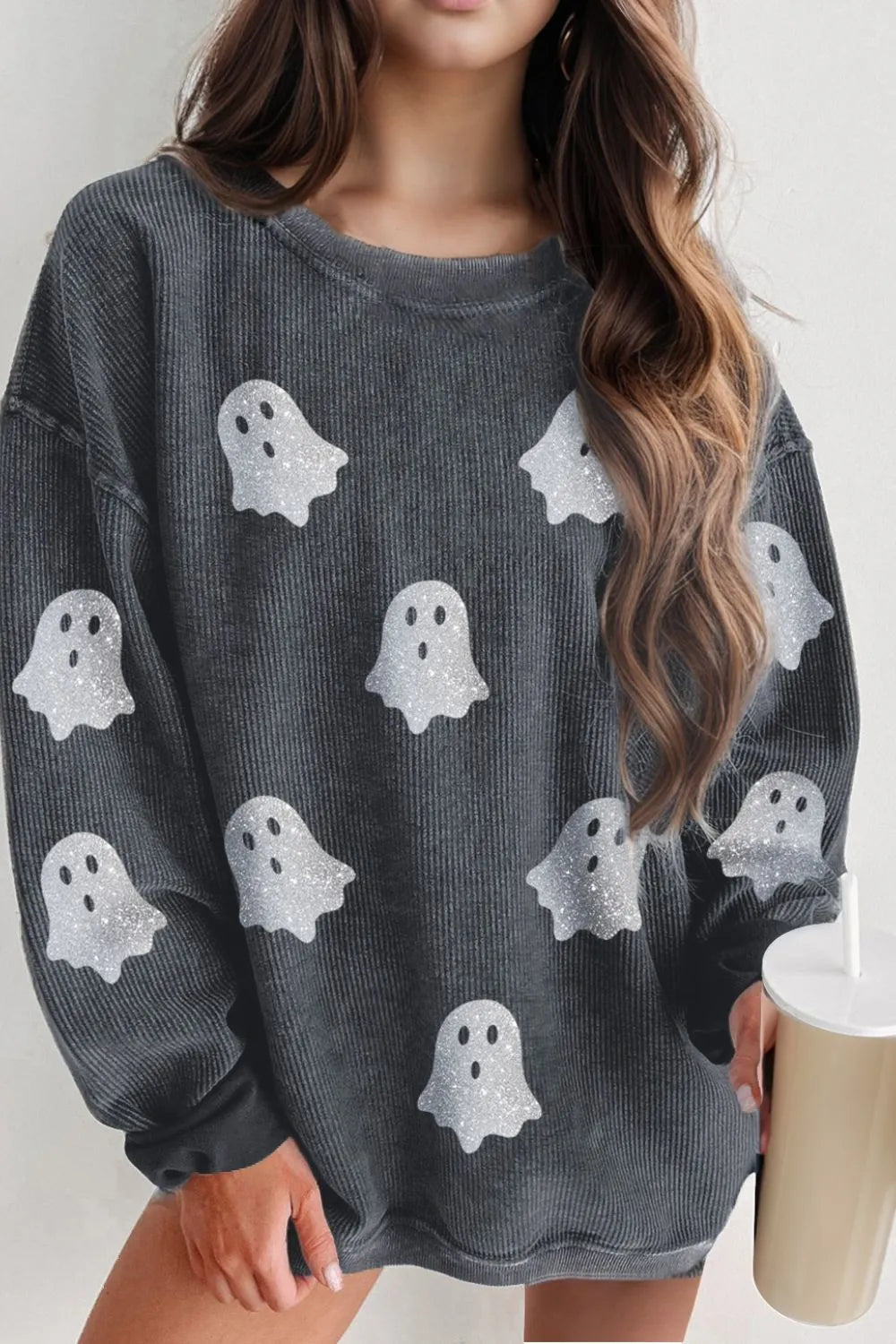 A woman wears a dark gray long-sleeve sweatshirt with glitter ghost graphics.