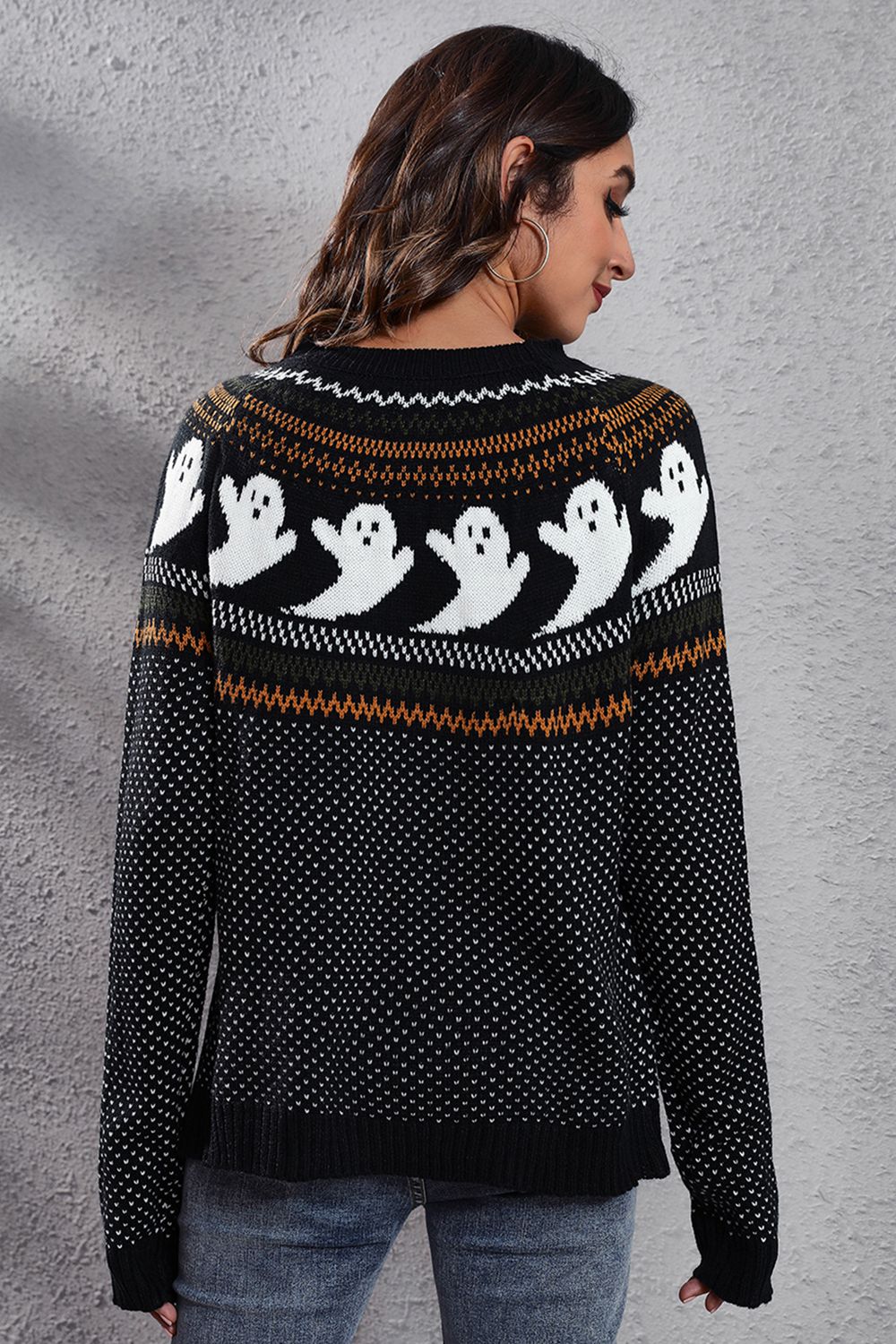 A woman from behind wears a black long-sleeve sweater with a ghost pattern.