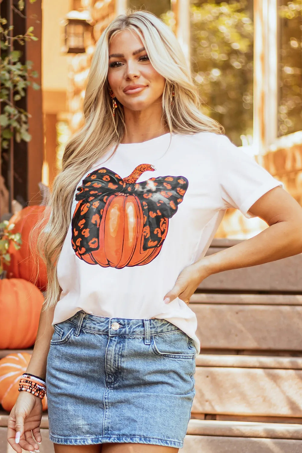 A woman wears a white short-sleeve t-shirt with a pumpkin graphic.