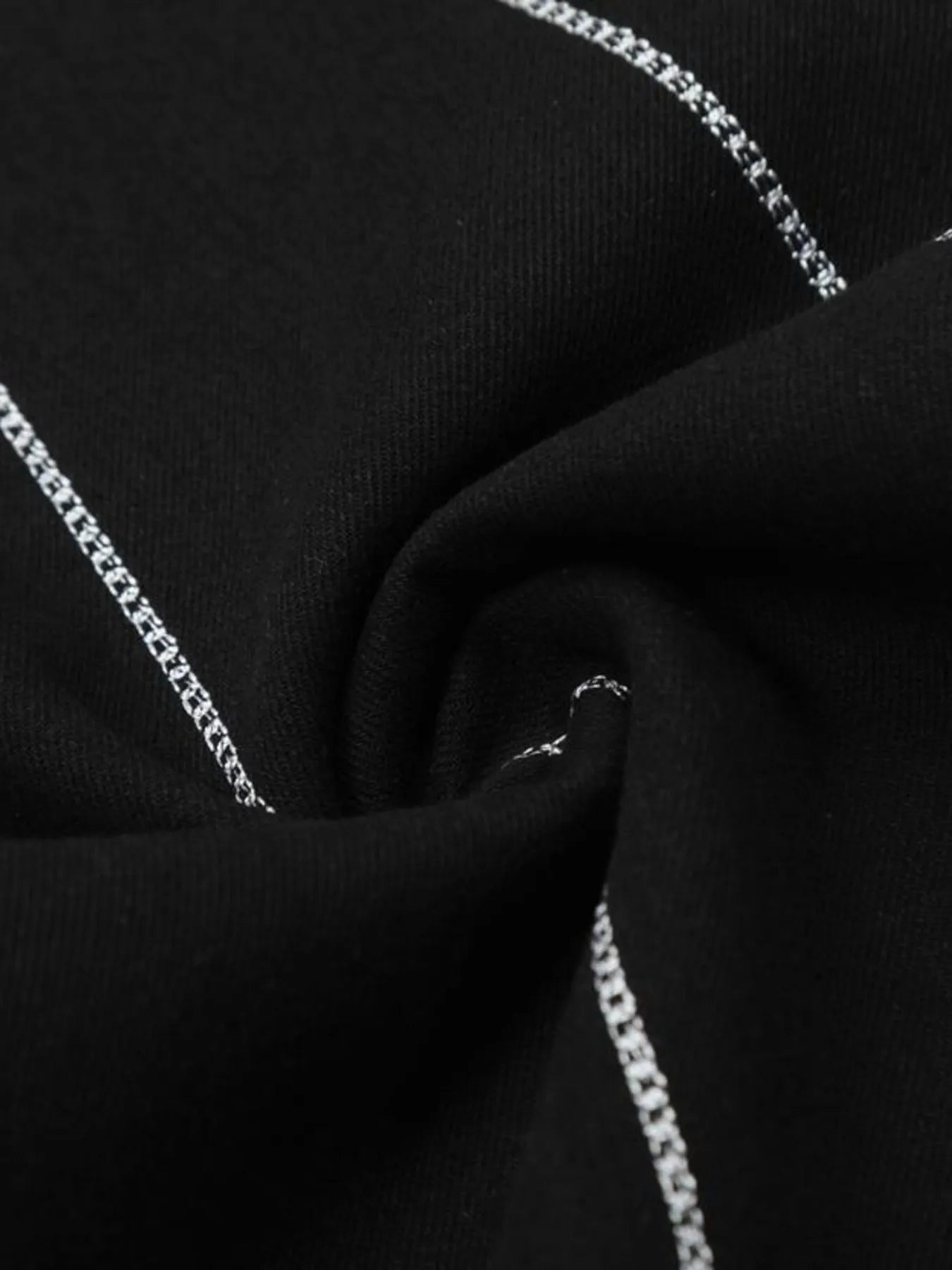 Close-up of black denim fabric with white chain-stitch seams.