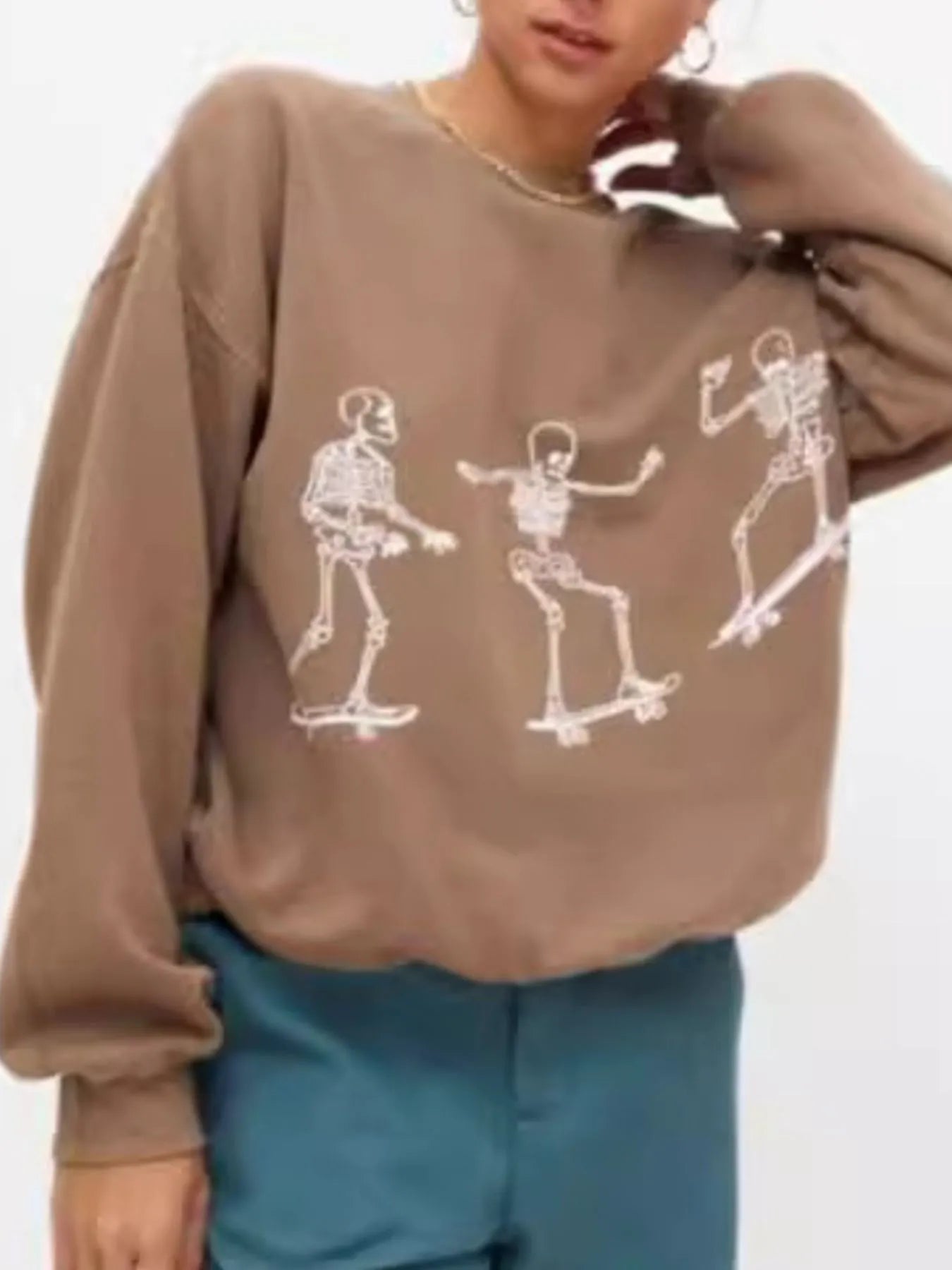 Oversized brown sweatshirt with three white skeleton graphics skateboarding.