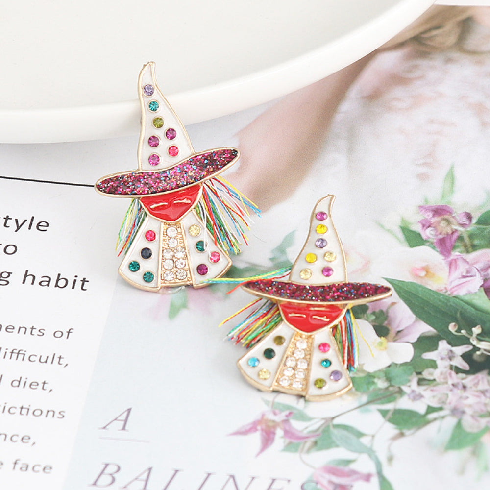 Two colorful witch-shaped rhinestone alloy earrings are displayed on a magazine.