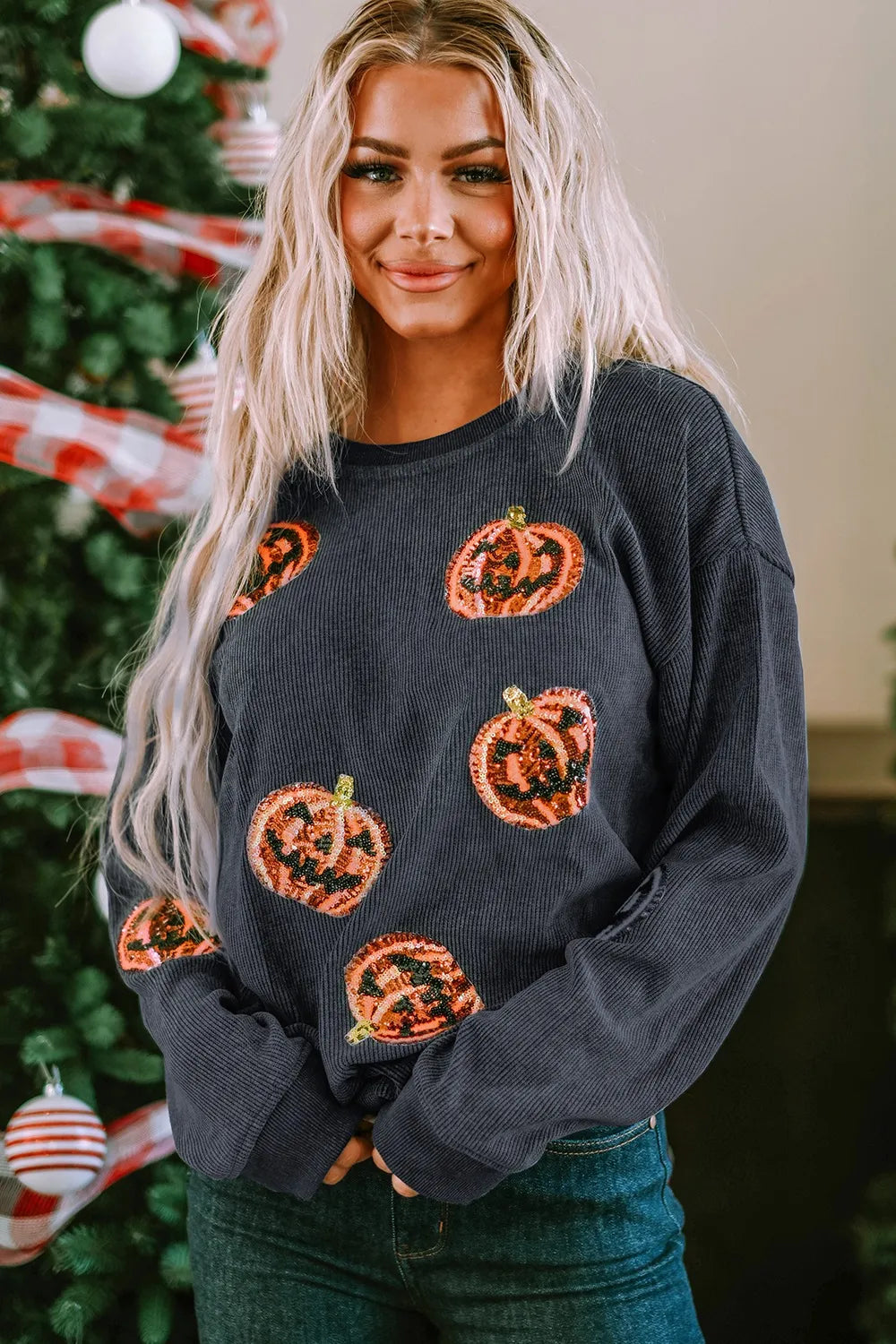Blonde woman wearing a dark gray sequin pumpkin round neck sweatshirt.
