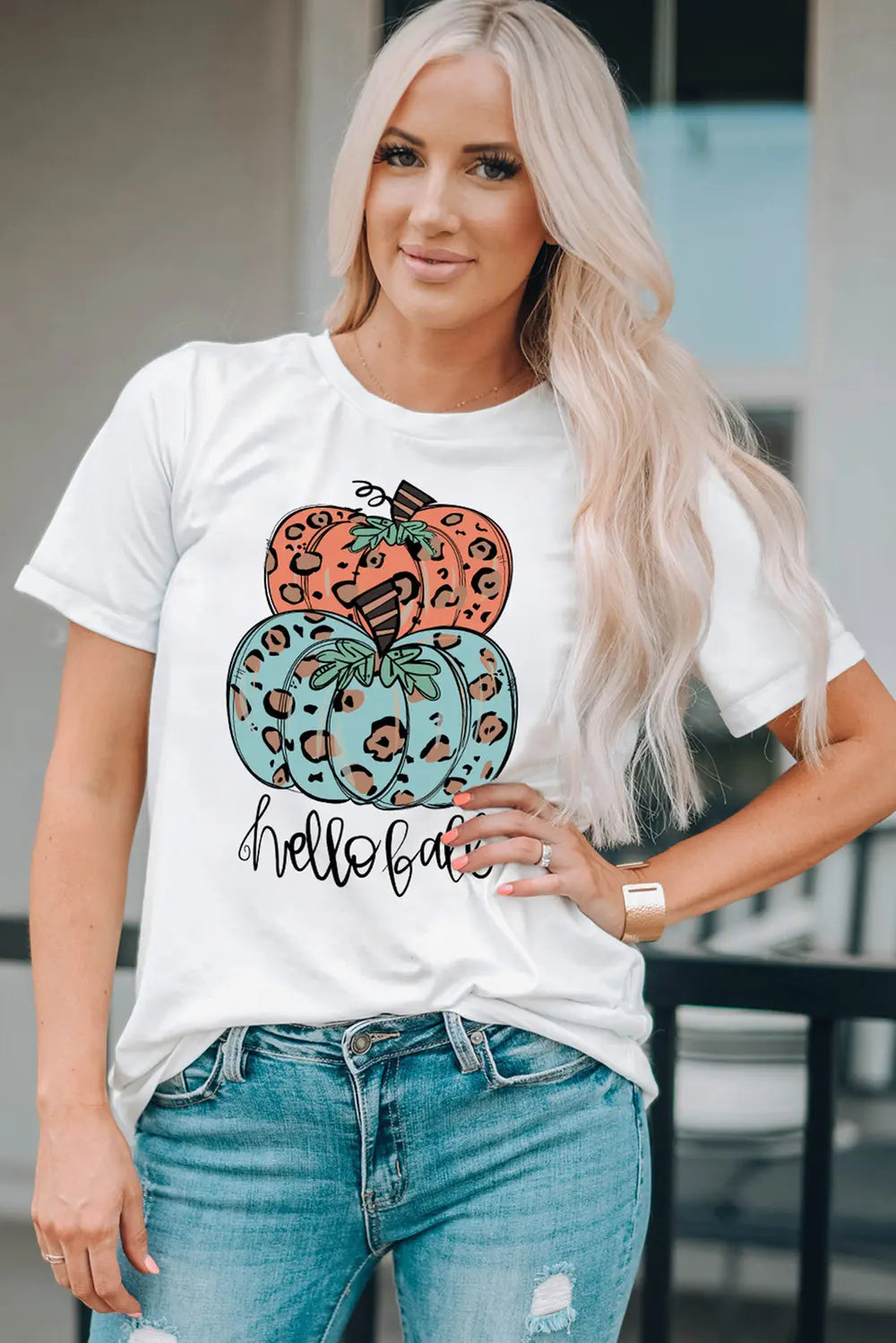 A woman wears a white short-sleeve t-shirt with a pumpkin graphic.