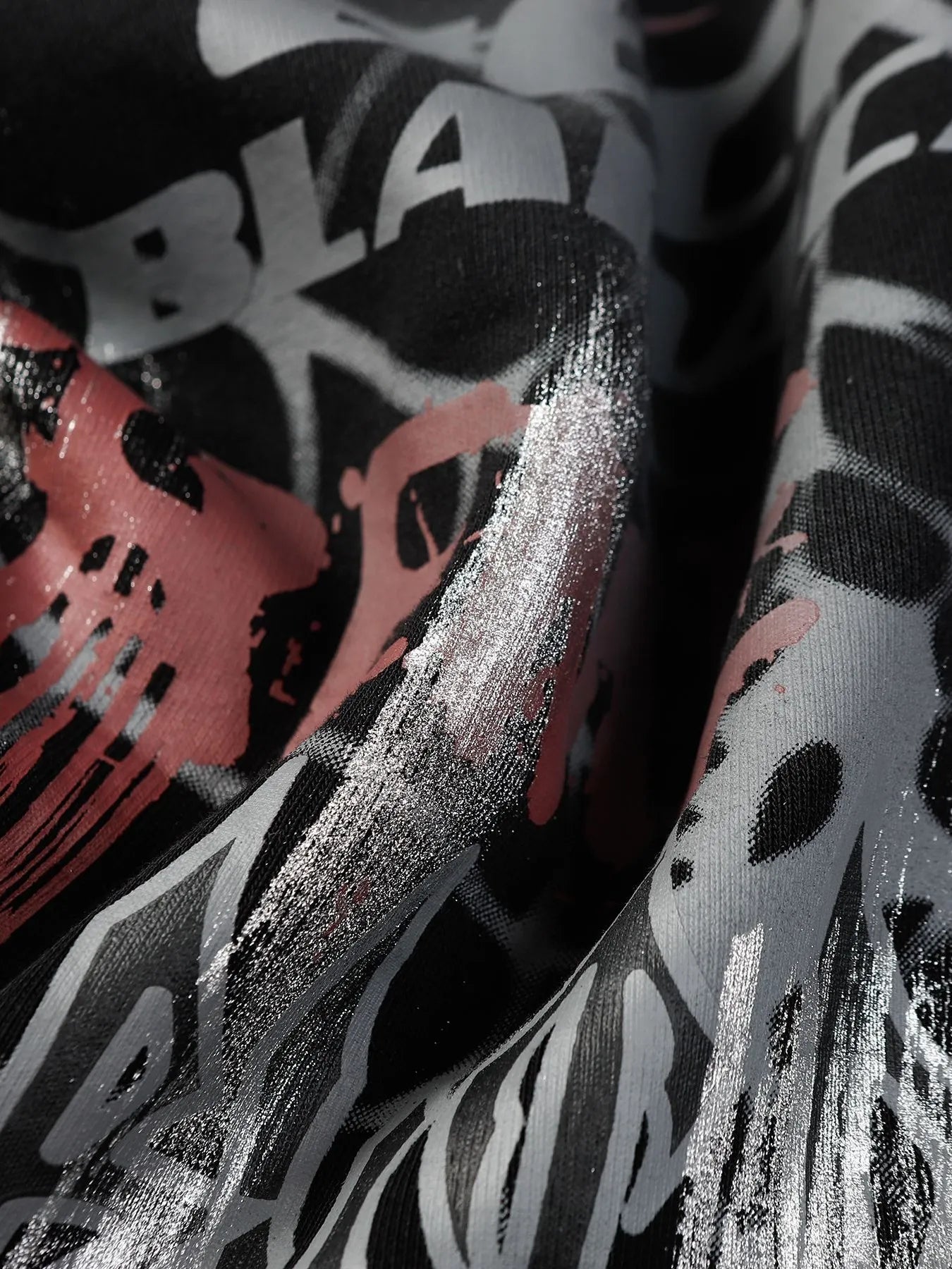 Close-up of a black fabric with white, grey, and pink graffiti-style print.
