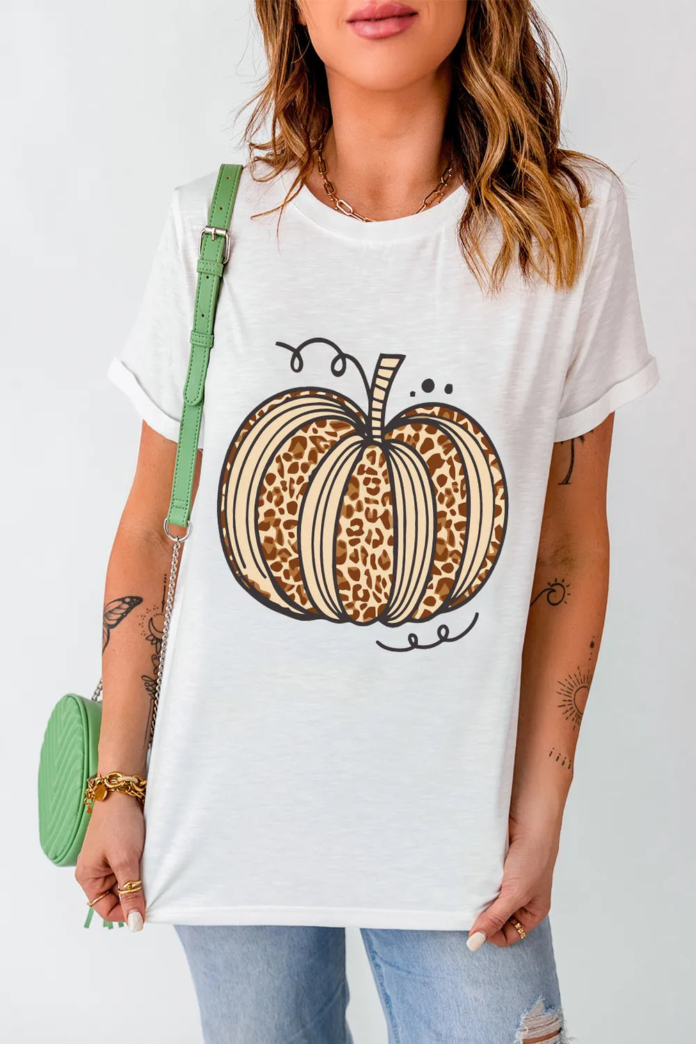 A woman wears a white short-sleeve t-shirt with a leopard print pumpkin design.