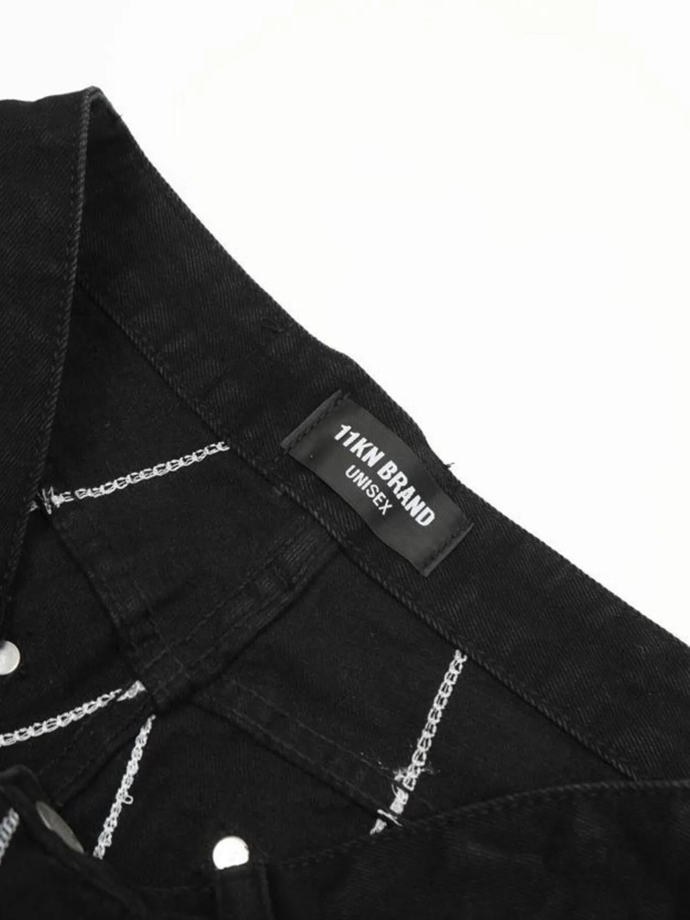 Black flared jeans with white spider web embroidery and a "11KN BRAND UNISEX" tag.