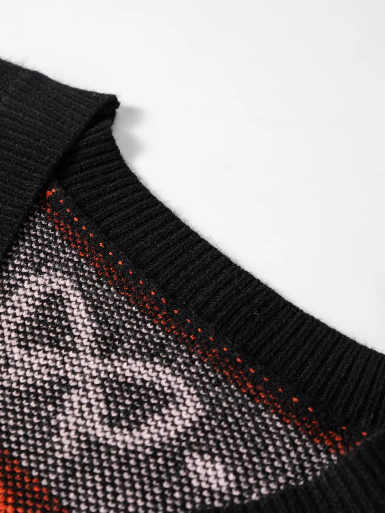 Close-up of a black cardigan with a white and orange pattern.
