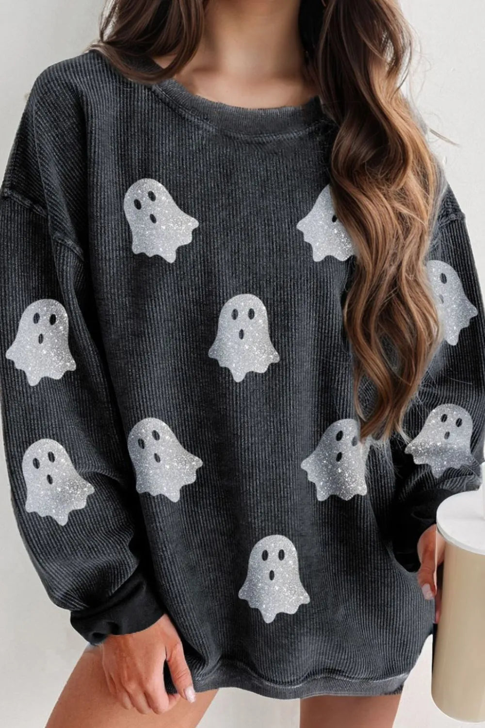 A woman wears a dark gray long-sleeve sweatshirt with glitter ghost graphics.