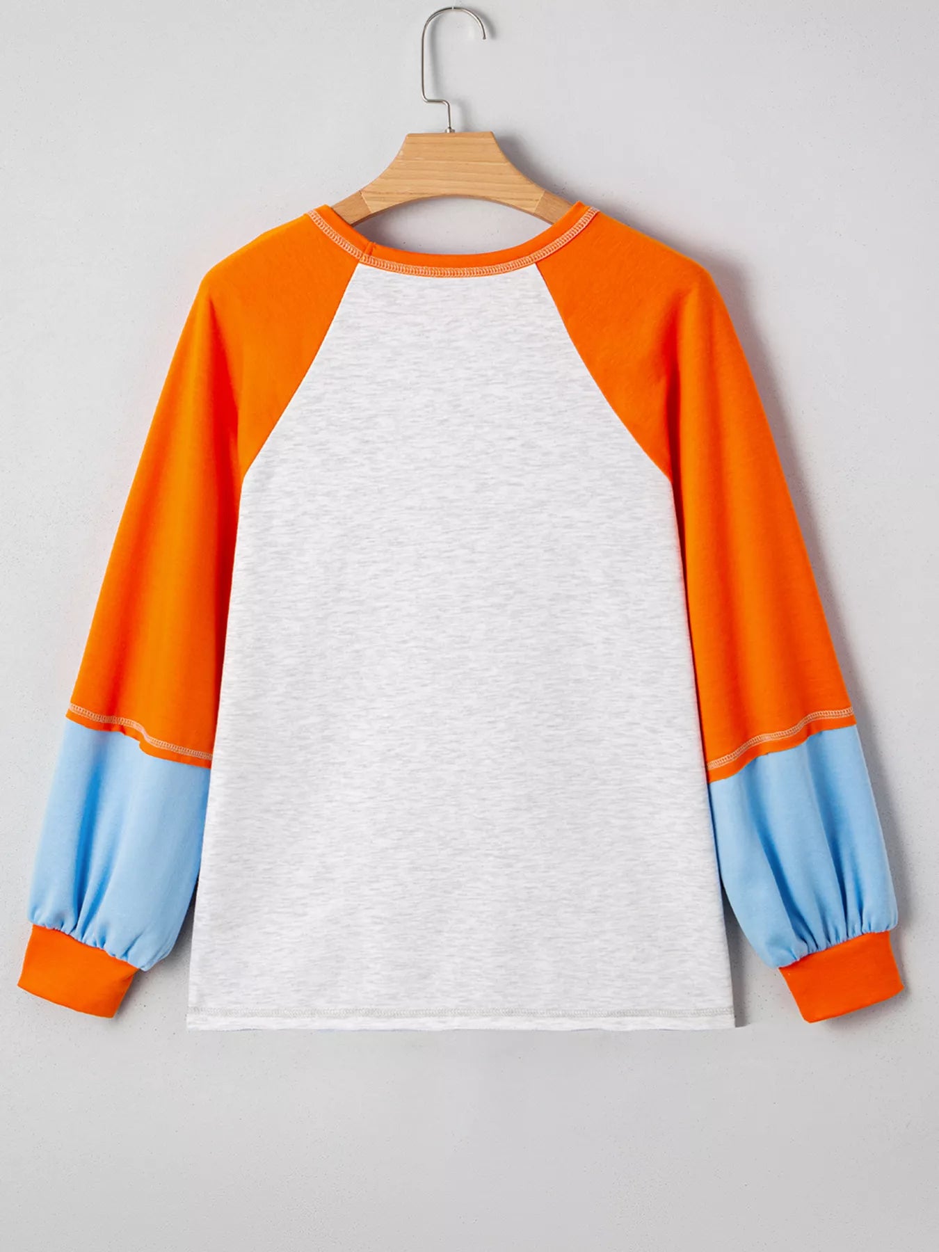 White long-sleeve t-shirt with orange raglan sleeves and light blue cuffs.