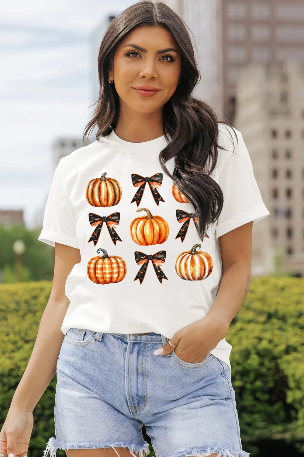 A woman wears a white short-sleeve t-shirt with pumpkin and bow graphics.