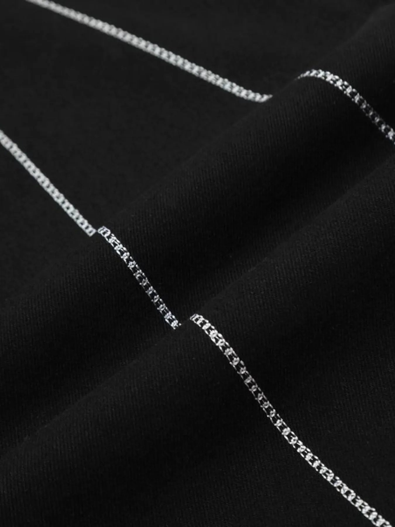 Black flared jeans with white spider web embroidery.