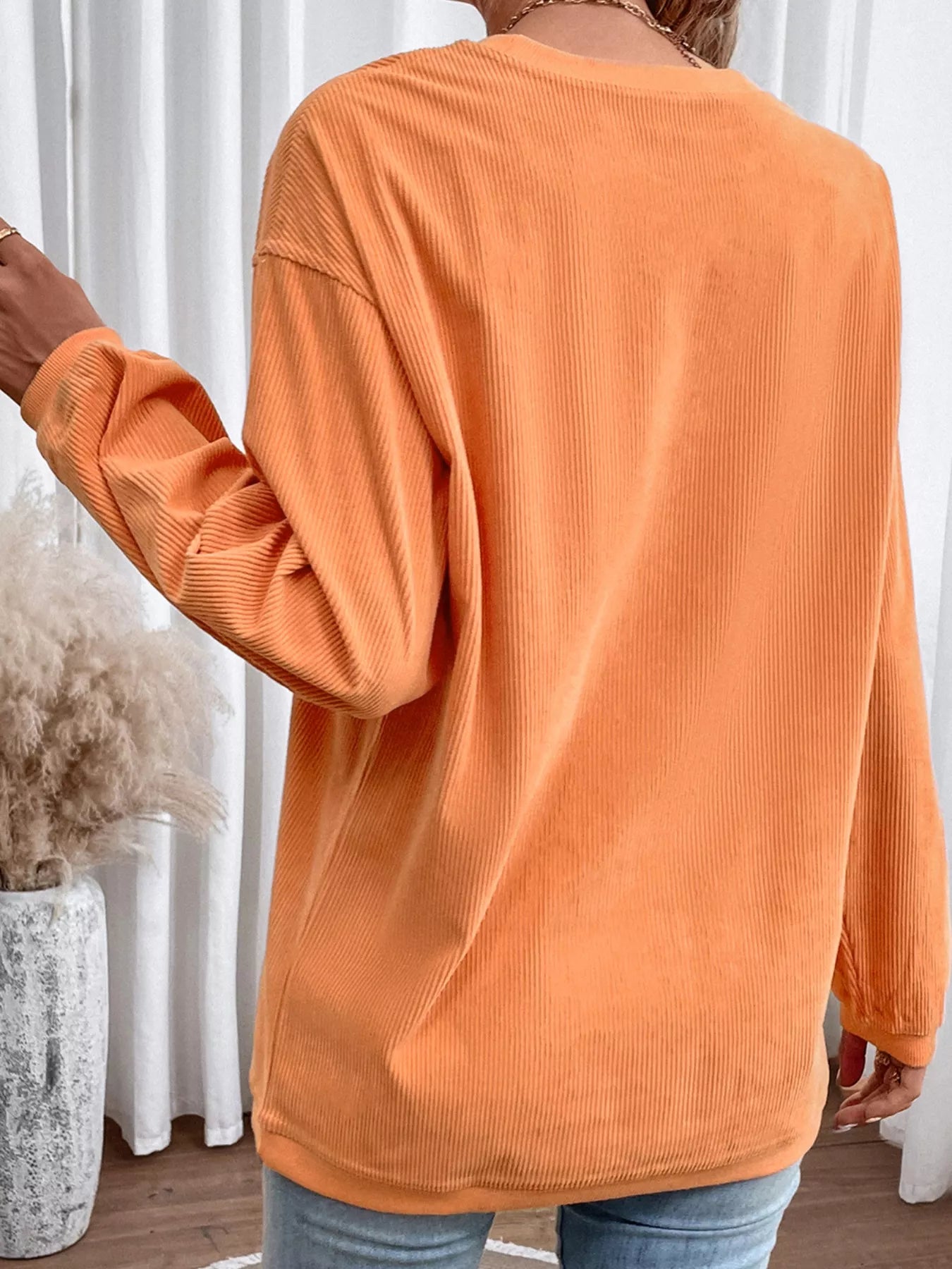 Orange ribbed long-sleeve sweatshirt with a round neck.