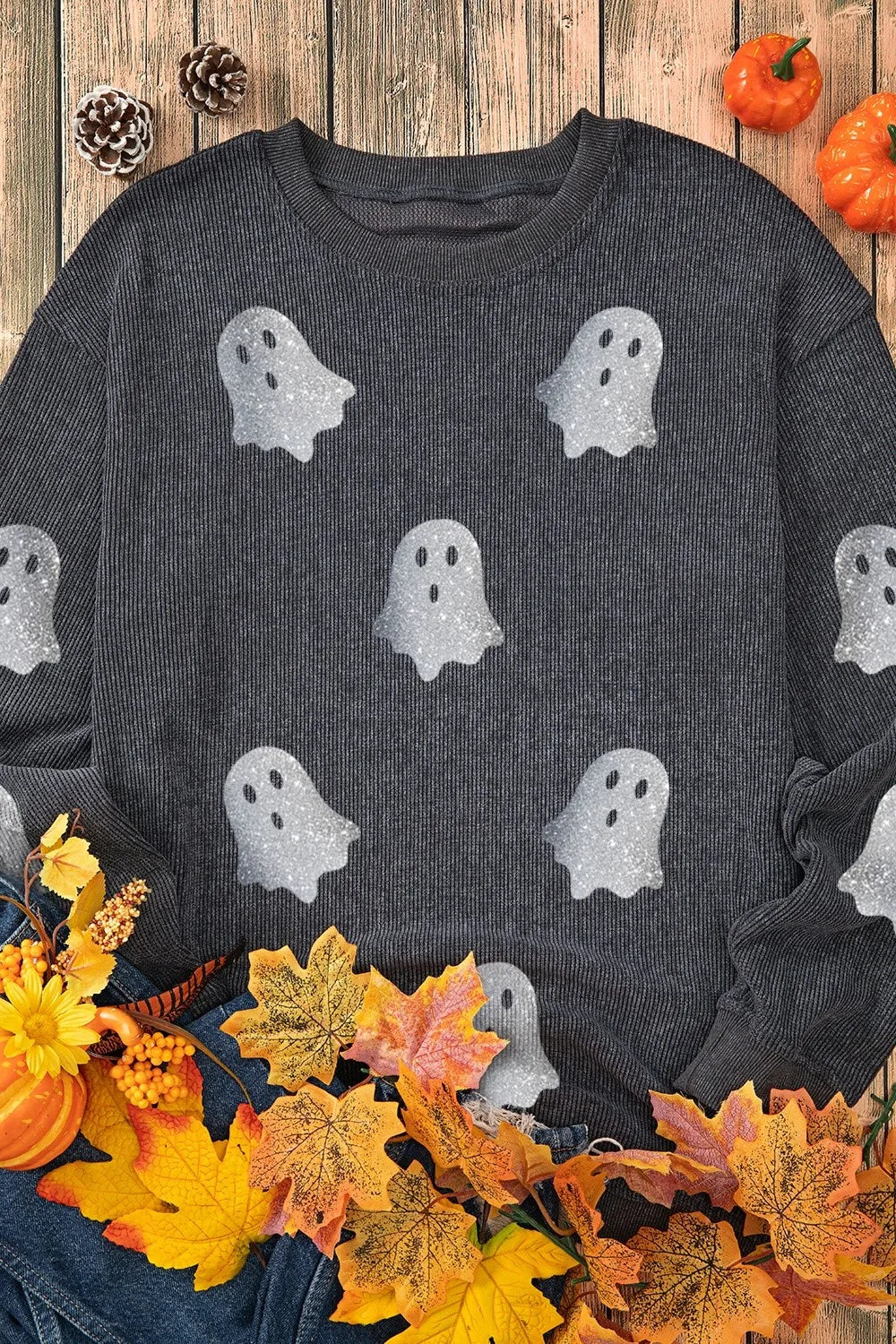 A dark gray long-sleeve sweatshirt with glitter ghost graphics is styled with autumn decor.