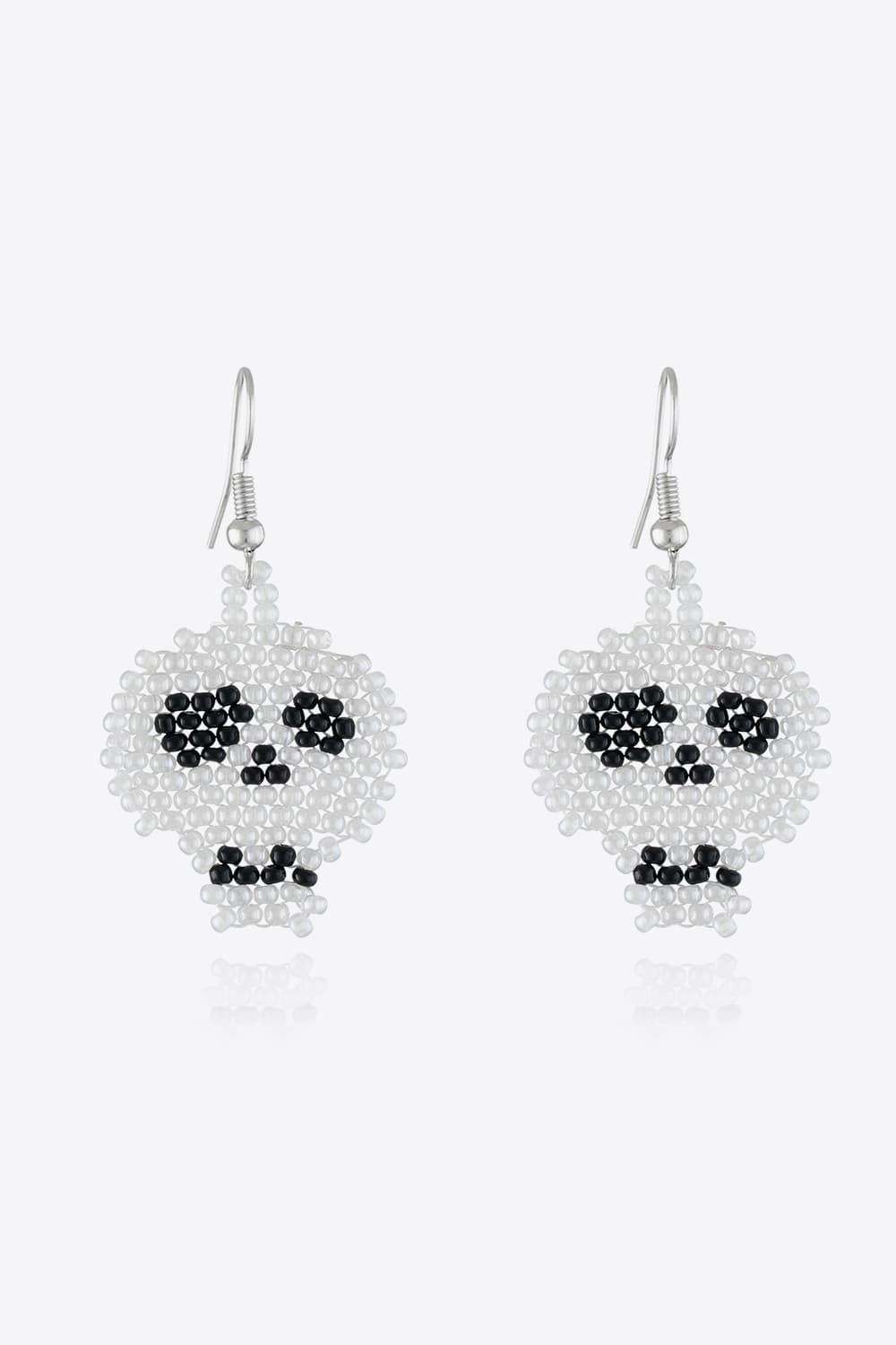 A pair of white beaded skull earrings with black eyes and nose.