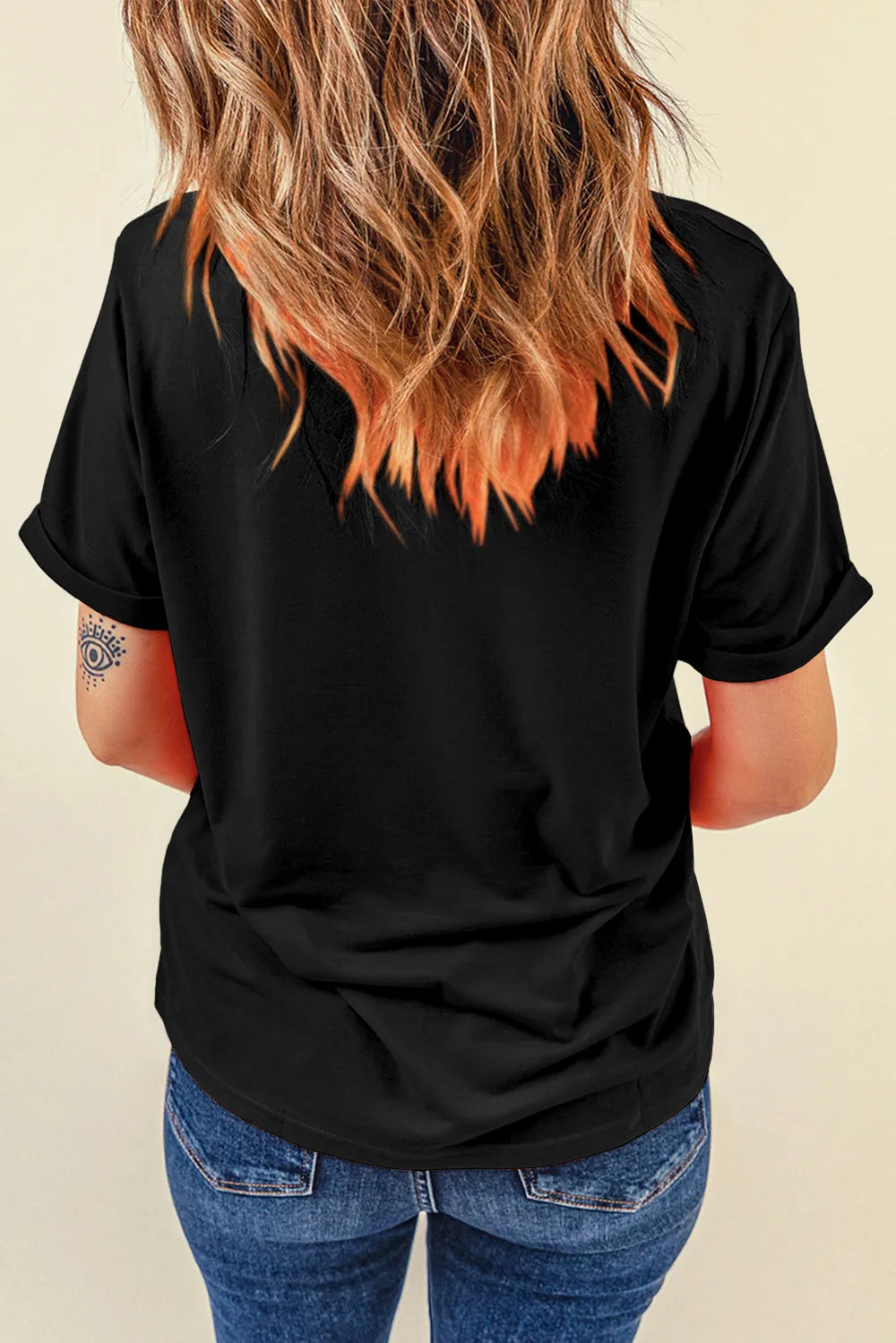 A woman from behind wears a black short-sleeve t-shirt and blue jeans.