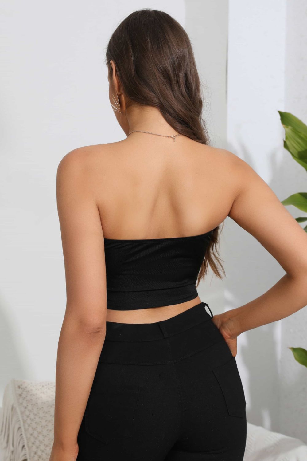 A woman from behind wears a black tube top and black pants.