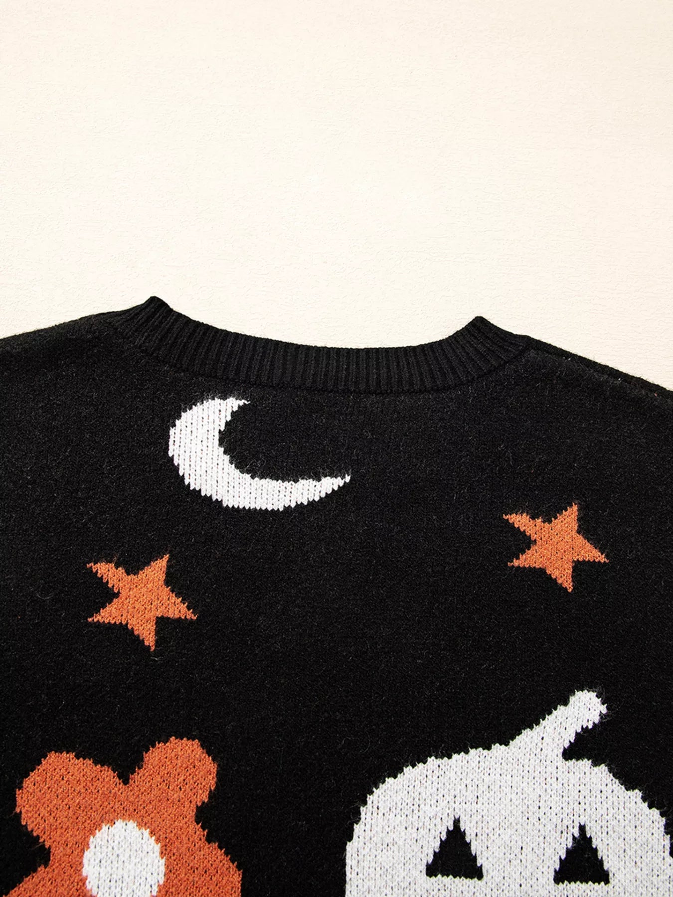 Black long-sleeve sweater with a white moon, orange stars, and a white pumpkin design.