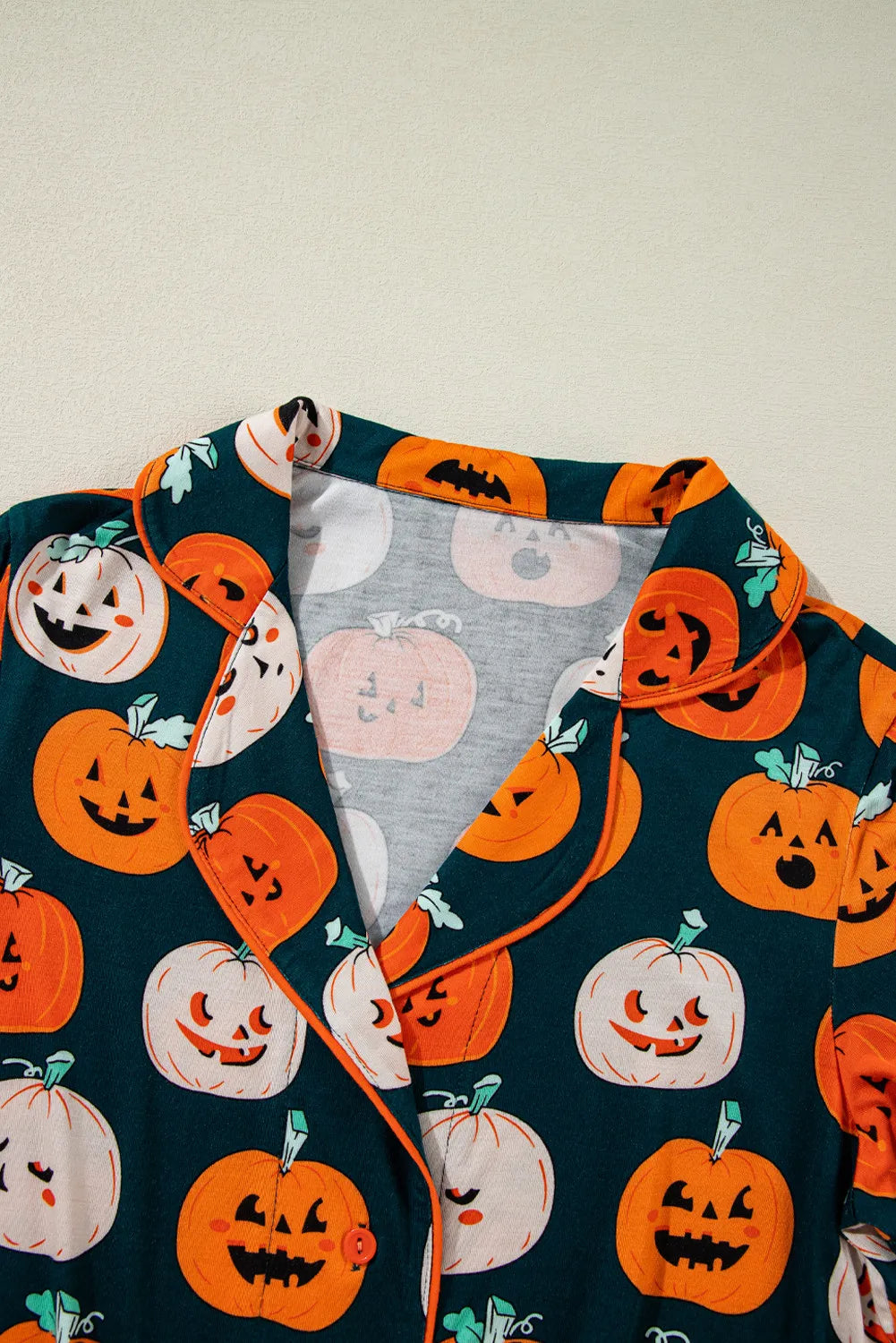 A dark green short sleeve top with an orange and white pumpkin print.