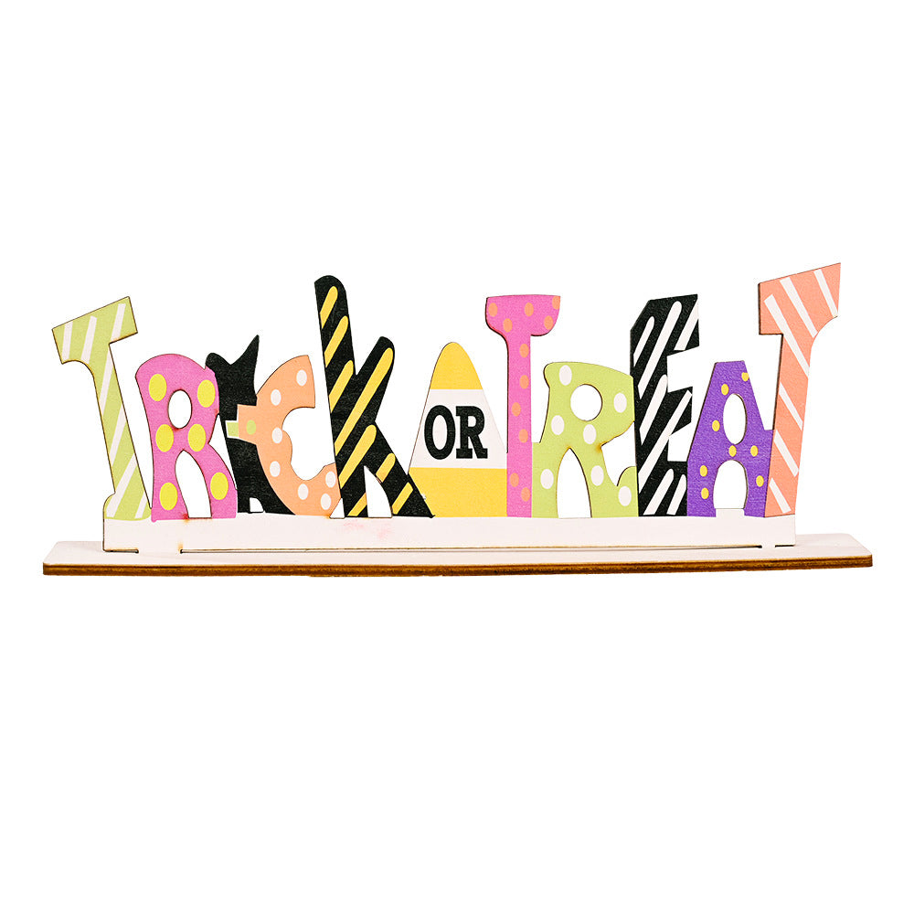 A colorful wooden "TRICK OR TREAT" sign with various patterns on a white base.