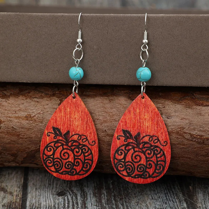 Turquoise and wood teardrop earrings with a black pumpkin design.