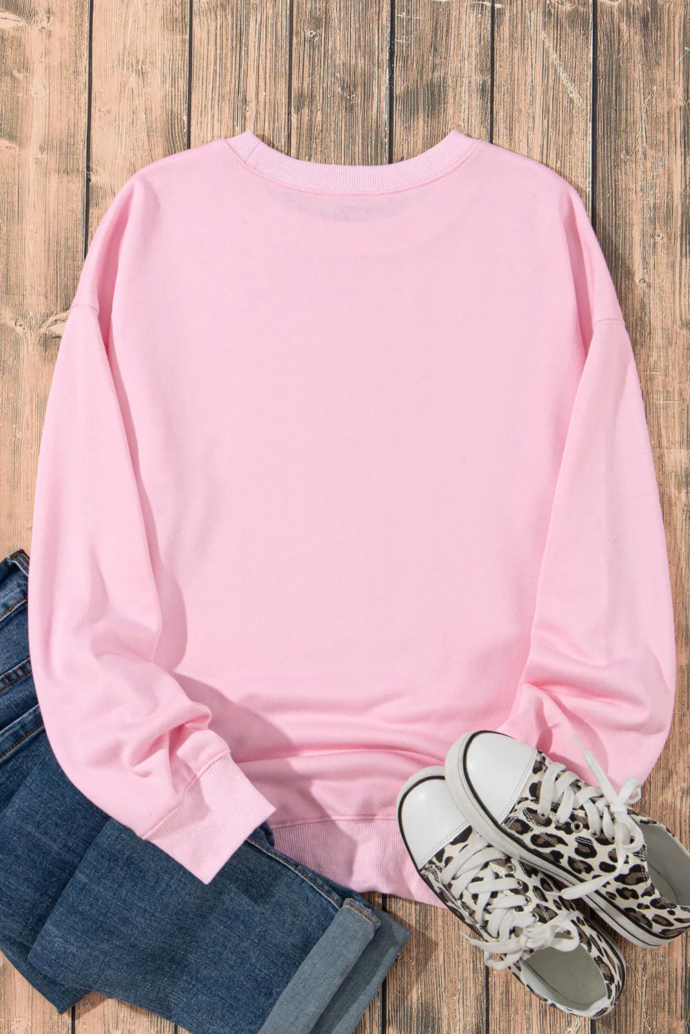 Pink round neck long sleeve sweatshirt with jeans and leopard print sneakers.