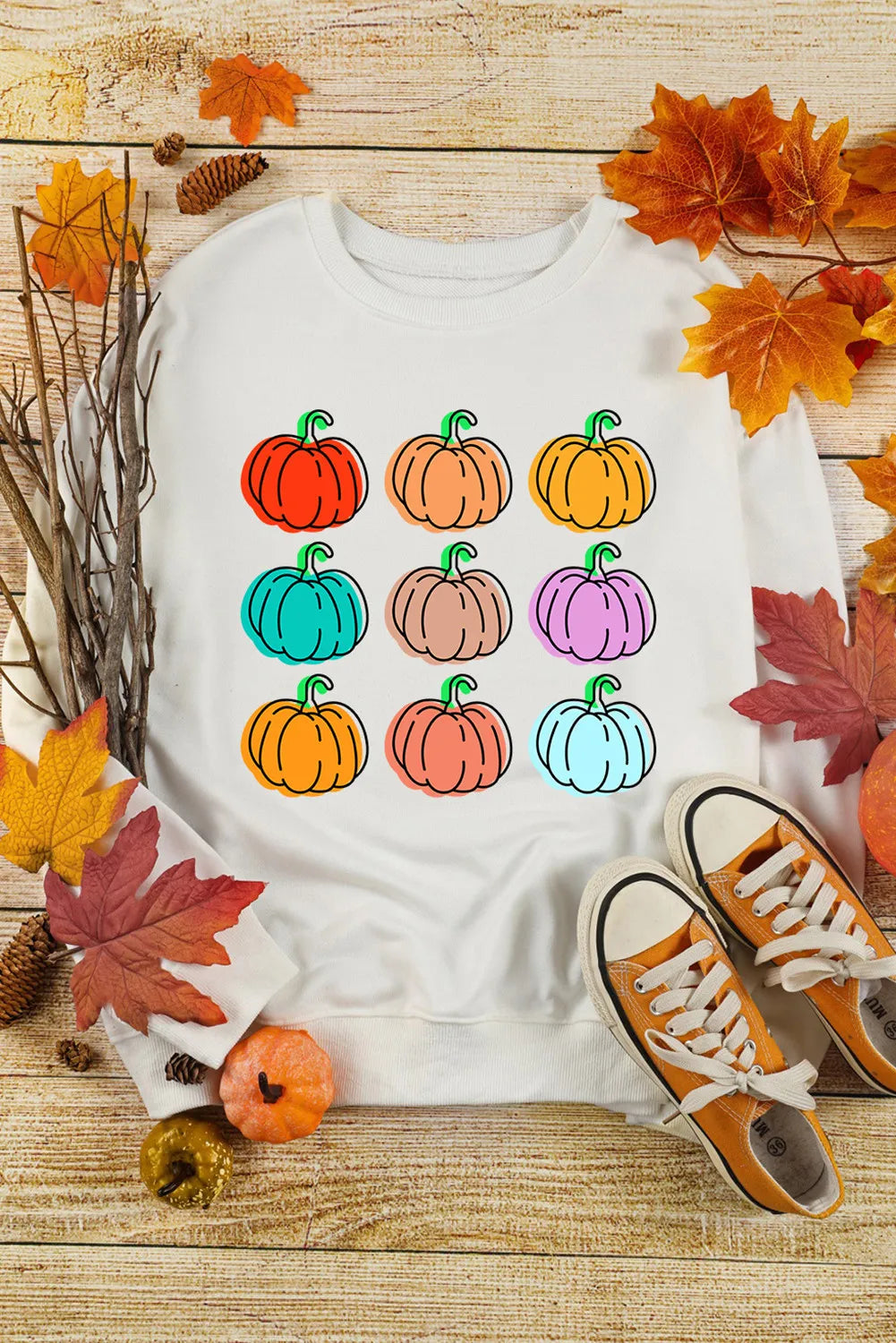 A white long-sleeve sweatshirt features nine colorful pumpkin graphics.
