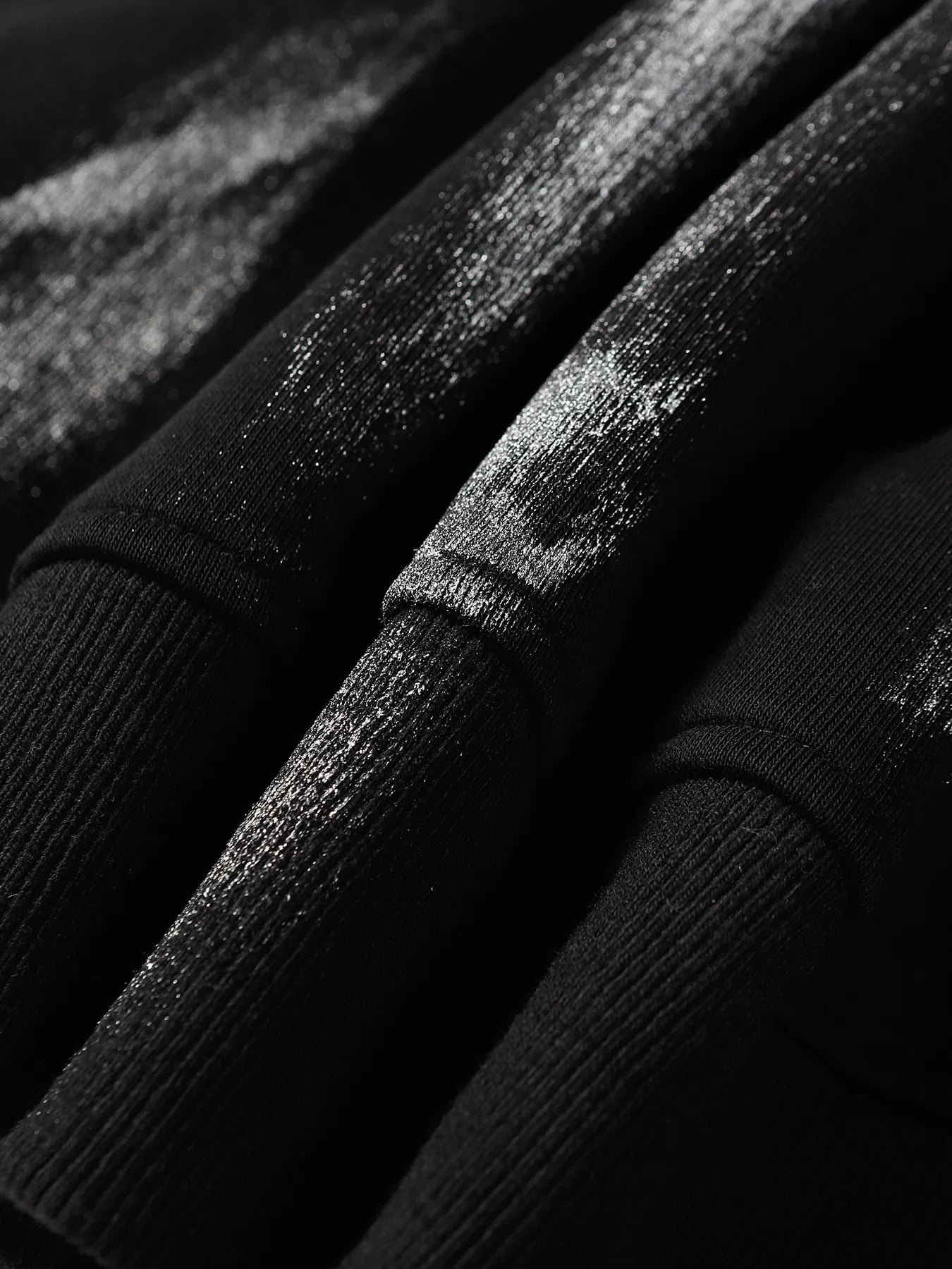 Close-up of a black hoodie with a subtle, shimmering spider web print.