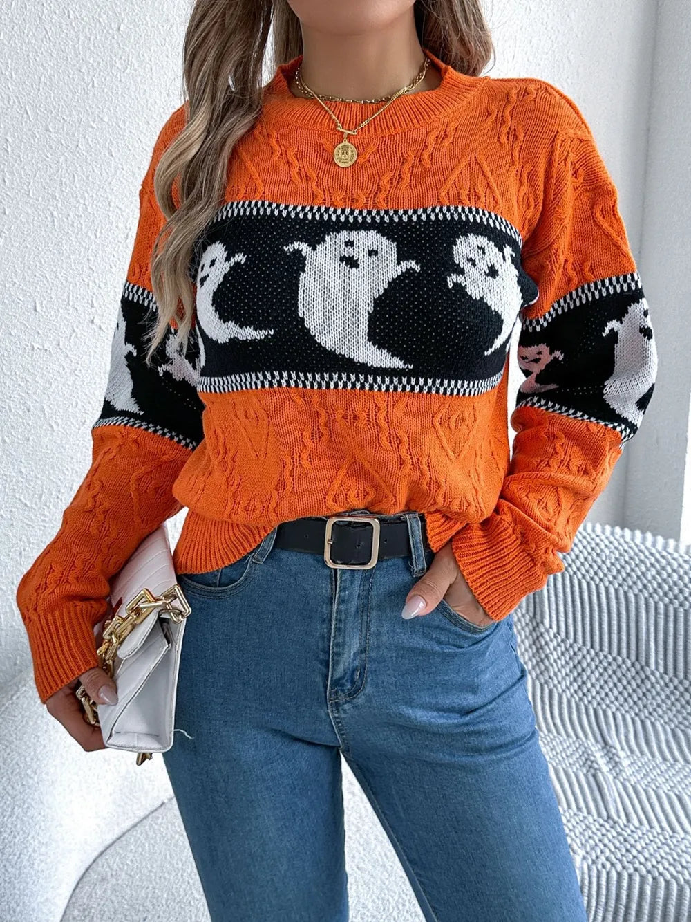 An orange long-sleeve sweater with a black and white ghost pattern.