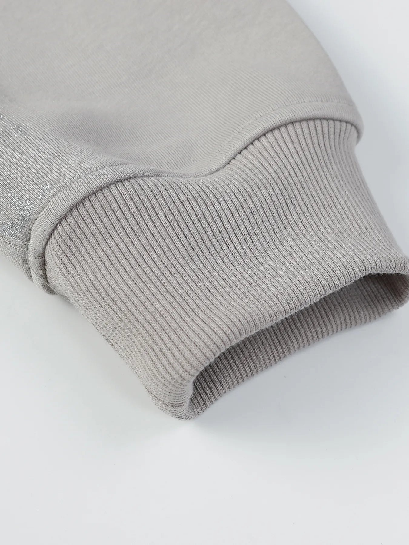 Close-up of a gray hoodie sleeve with a ribbed cuff.