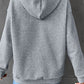 A person from behind wearing a gray waffle knit hoodie and blue jeans.