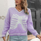A woman wears a purple V-neck sweater with a white skeleton pattern.