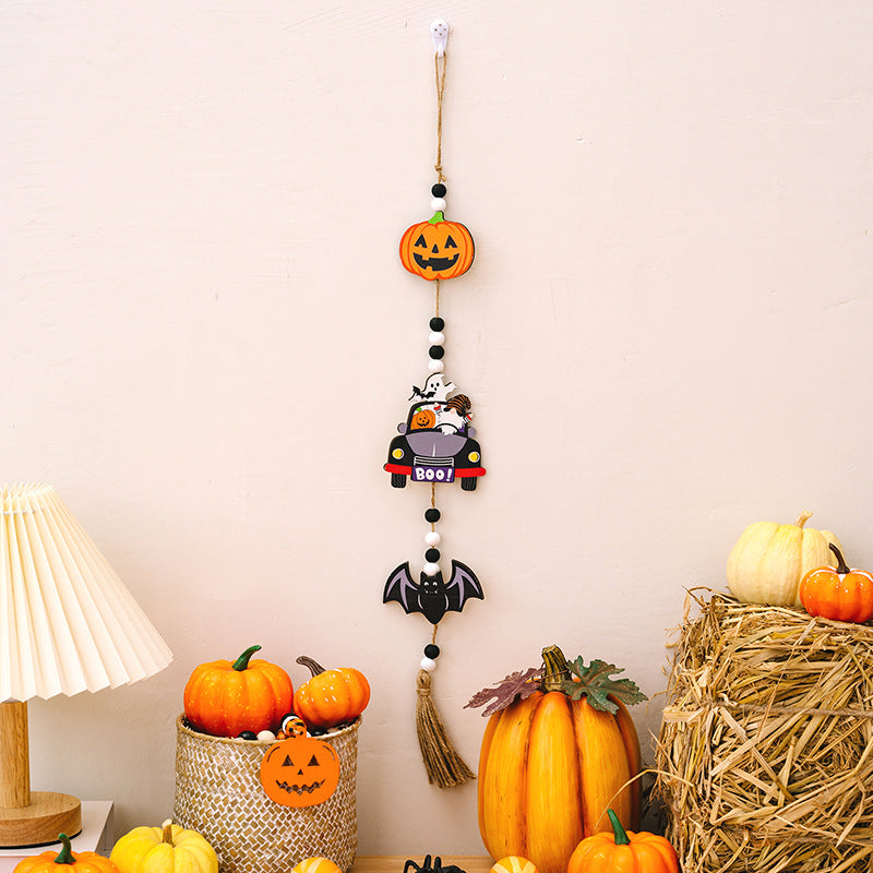 A Halloween hanging decoration featuring a pumpkin, a car with ghosts, and a bat.