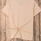 A light orange short-sleeve t-shirt with a knotted hem is displayed on a wooden background.