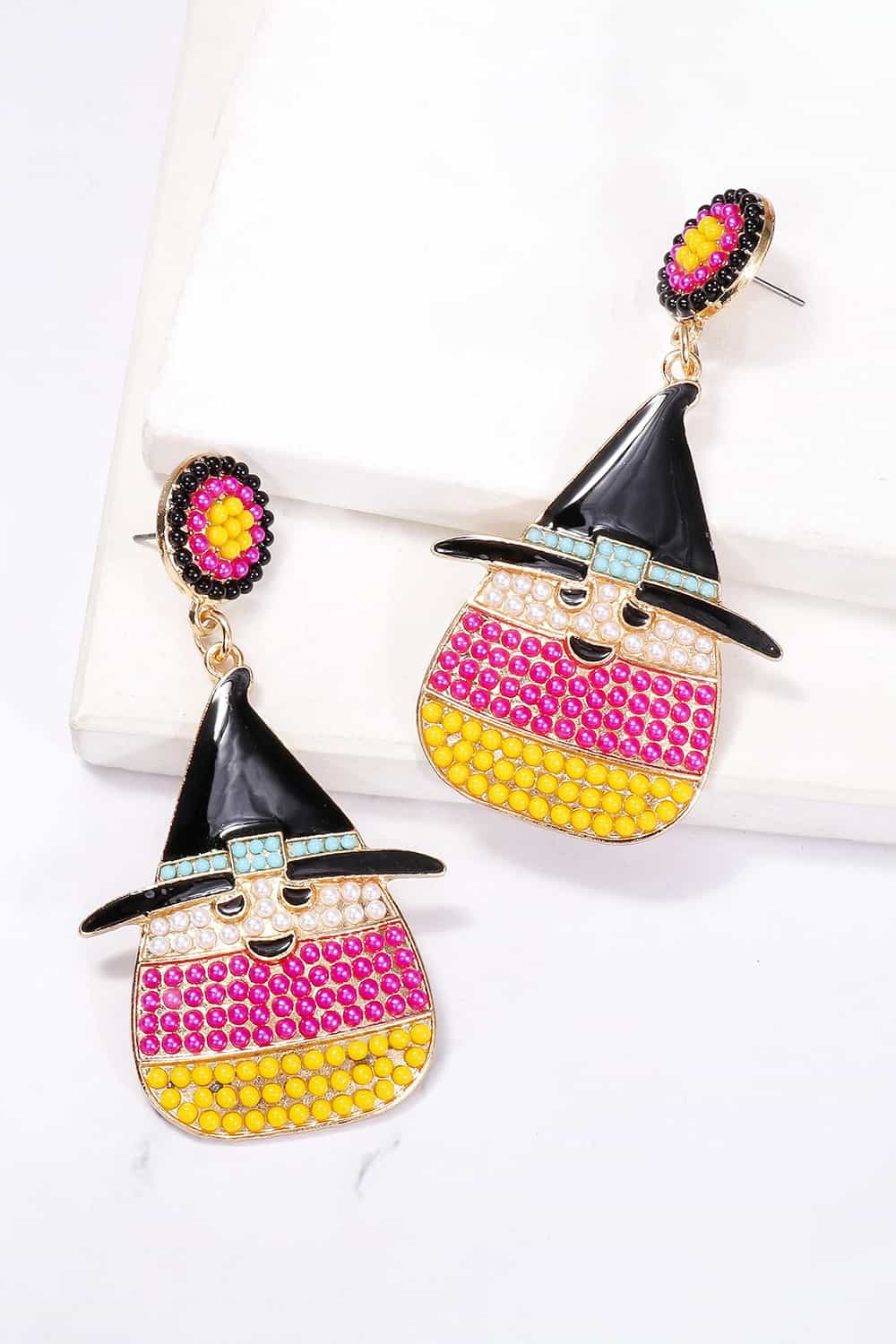 Pair of dangle earrings featuring a witch's hat and candy corn design with synthetic pearls.