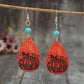 Turquoise wooden pumpkin teardrop earrings hang from a branch.