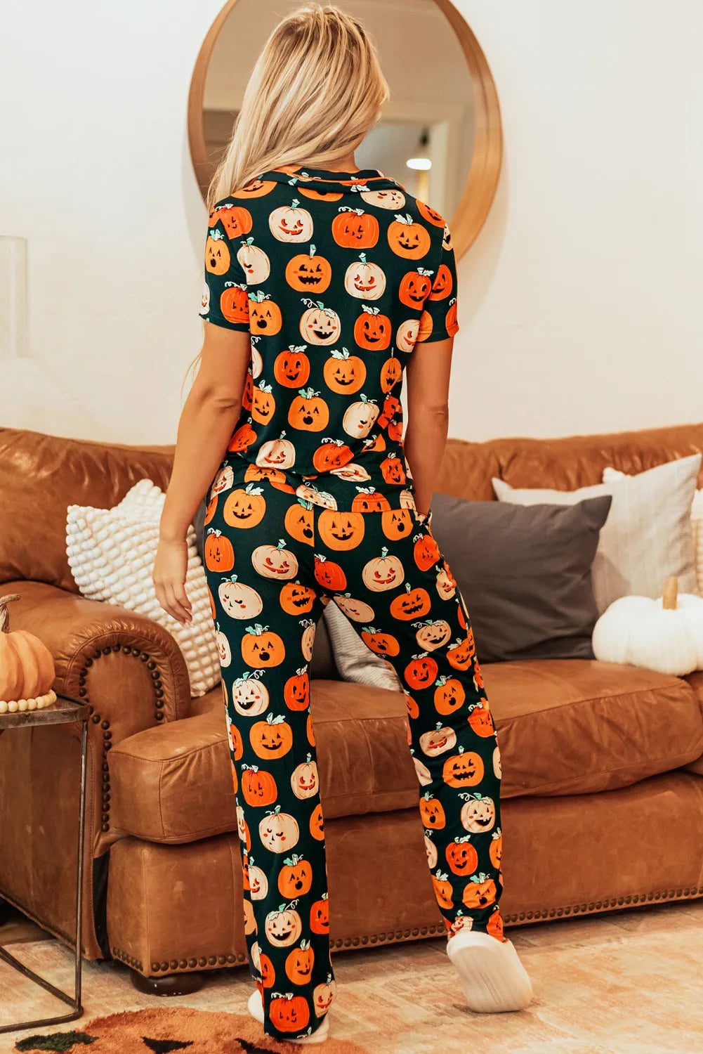 A woman from behind wears a pumpkin-printed short sleeve top and pants lounge set.